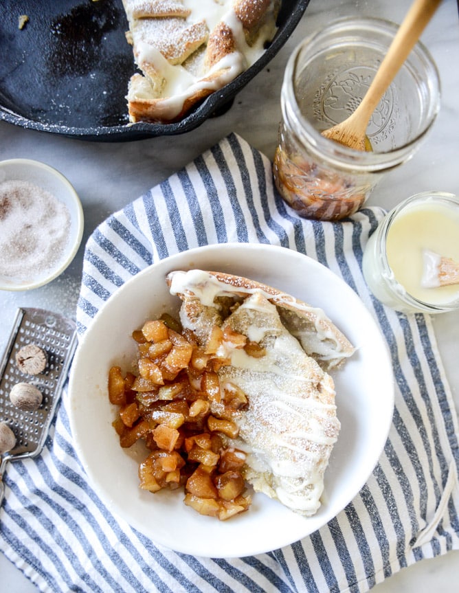 vanilla cinnamon roll dutch baby with apple bourbon compote and cream cheese icing I howsweeteats.com