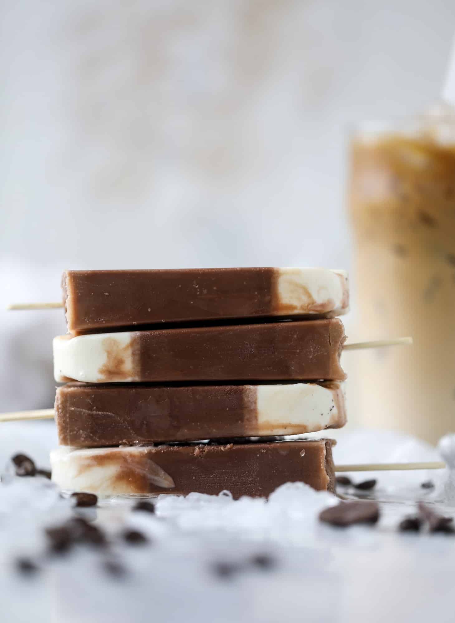 These fudgesicles are made with cold brew and dutch process cocoa for the most fun grown-up popsicle that can also deliver a little caffeine jolt. Topped with vanilla bean sweet cream, these are just like an iced latte in a pop! Serve as a treat or a snack! I howsweeteats.com #coldbrew #coffee #sweet #cream #popsicle #fudgesicle