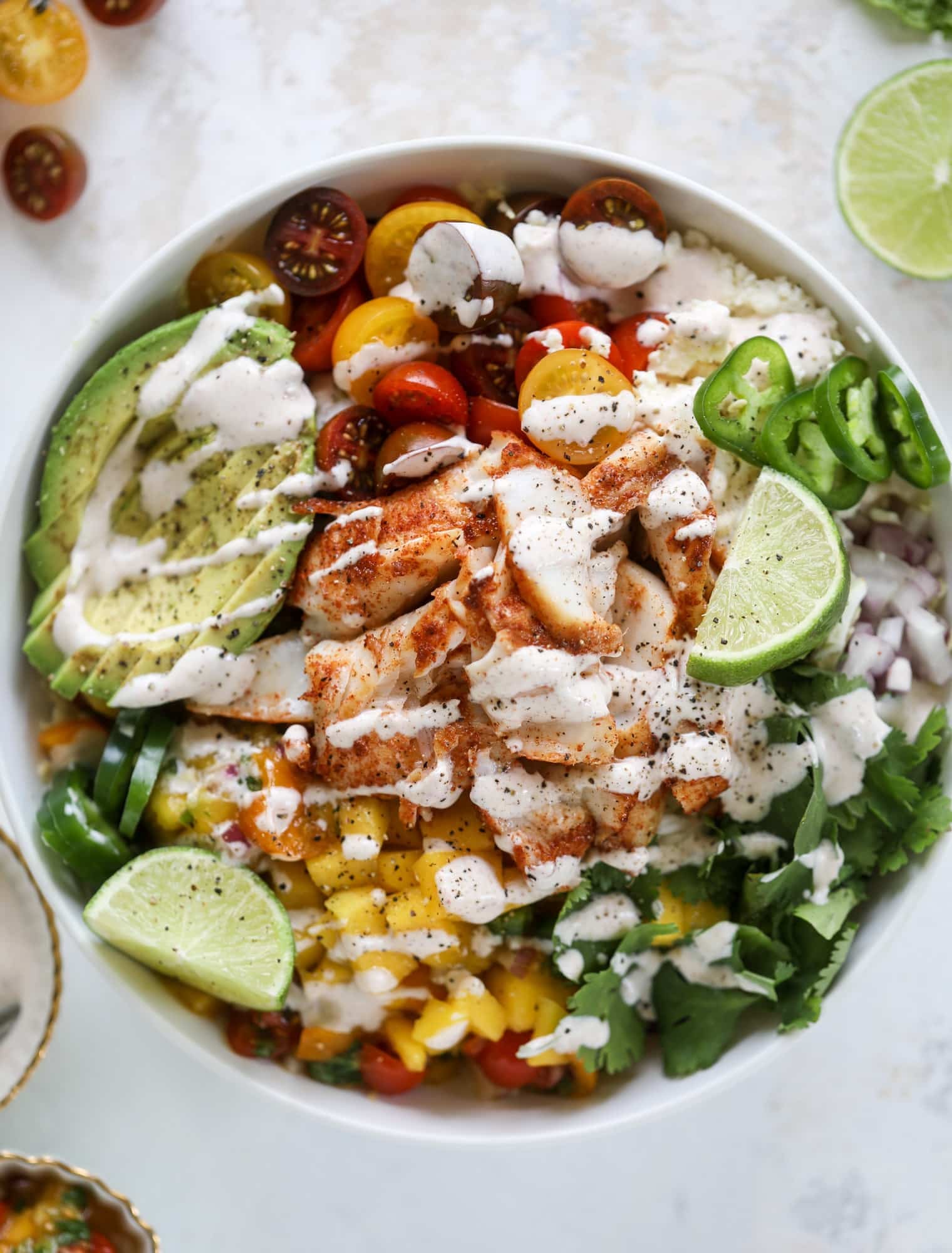 These fish taco bowls are an amazing weeknight meal idea! Napa cabbage for the base, a homemade chipotle crema, avocado, mango pico de gallo, spicy broiled white fish and lots of lime. Major flavor explosion and so easy too! I howsweeteats.com #fish #taco #bowls #spicy #healthy #dinner