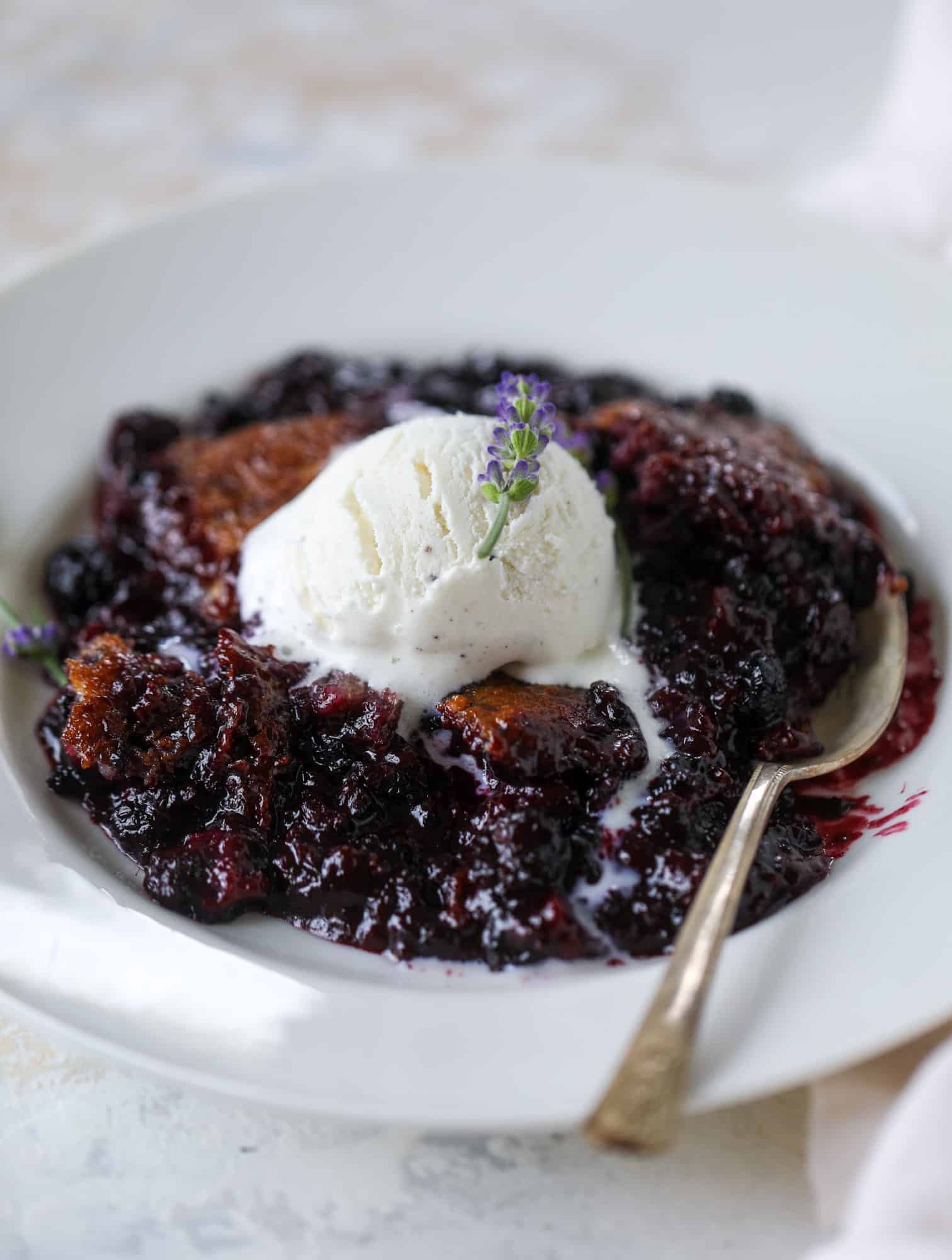 This black raspberry cobbler is a summer dream come true! The bursting black raspberries are rich and sweet, then add in a touch of lavender for incredible flavor and you're all set. The cobbler cake topping is perfect for vanilla ice cream. Win! I howsweeteats.com #black #raspberry #cobbler #lavender #summer #desserts #icecream