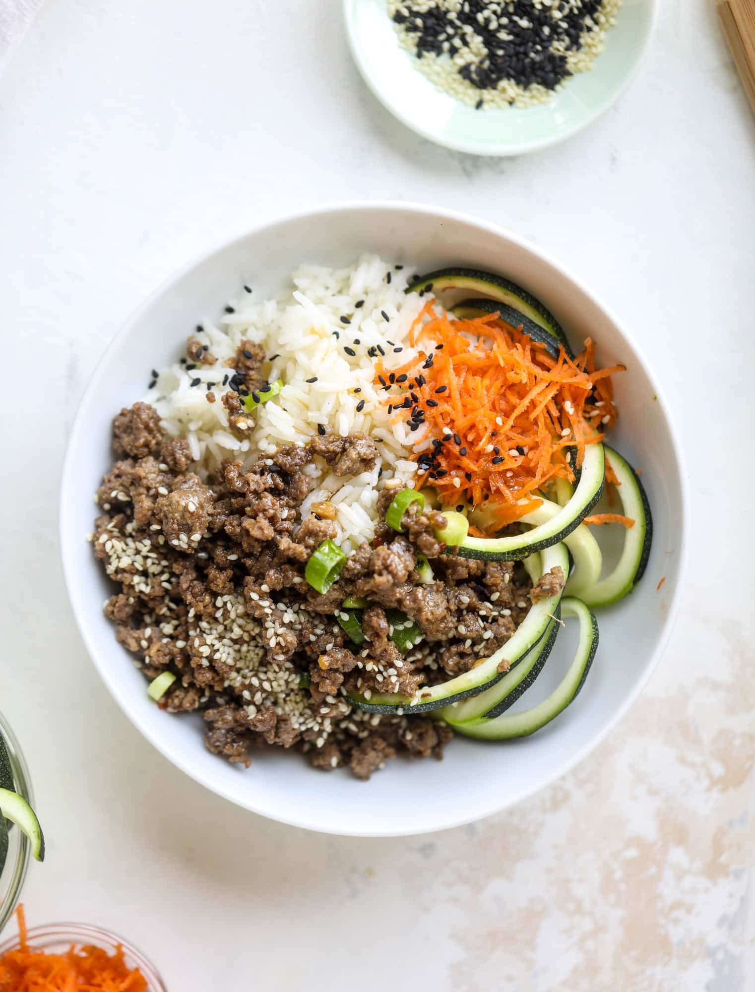 These korean beef bowls are so packed full of flavor that you won't want to eat anything else! Serve the beef with zucchini noodles, grated carrot and jasmine rice for a satisfying, flavor-packed bowl that comes together easily and quick! I howsweeteats.com #korean #beef