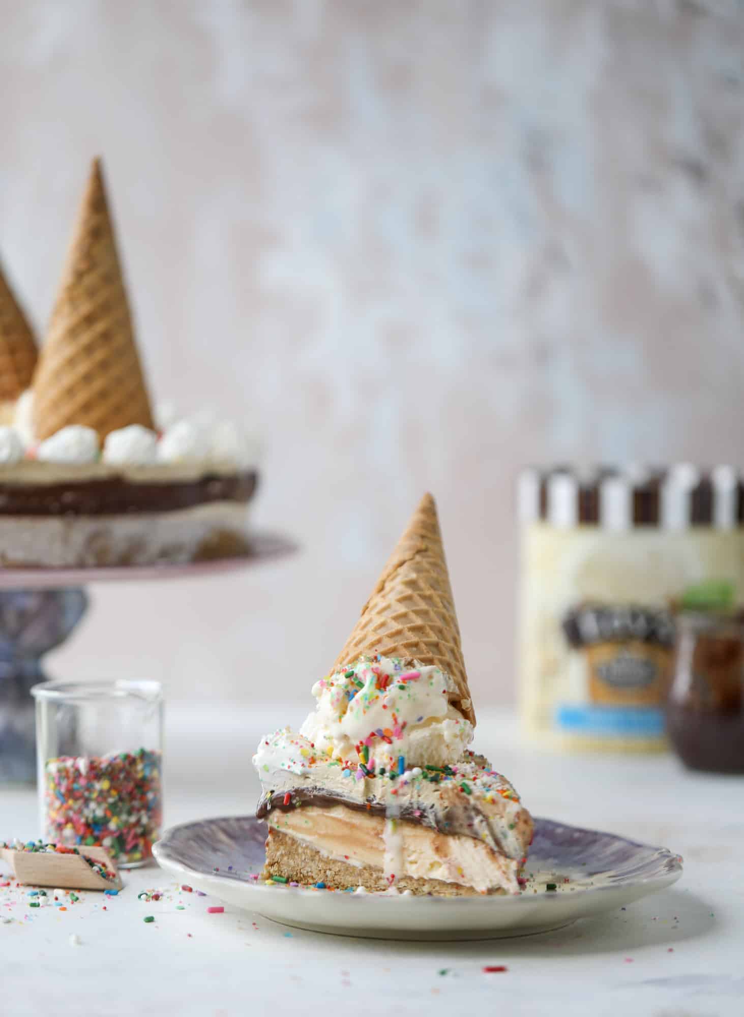 This peanut butter fudge ice cream cake is absolutely insane and perfect for summer! A sweet and savory pretzel crust, vanilla ice cream, homemade hot fudge and a peanut butter whipped cream layer take it to the next LEVEL. Delicious! I howsweeteats.com #icecream #cake #peanutbutter #chocolate #pretzel