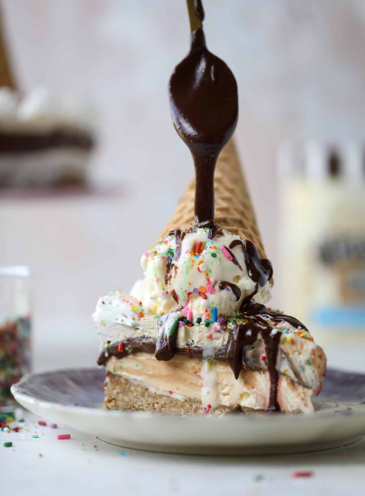 This peanut butter fudge ice cream cake is absolutely insane and perfect for summer! A sweet and savory pretzel crust, vanilla ice cream, homemade hot fudge and a peanut butter whipped cream layer take it to the next LEVEL. Delicious! I howsweeteats.com #icecream #cake #peanutbutter #chocolate #pretzel