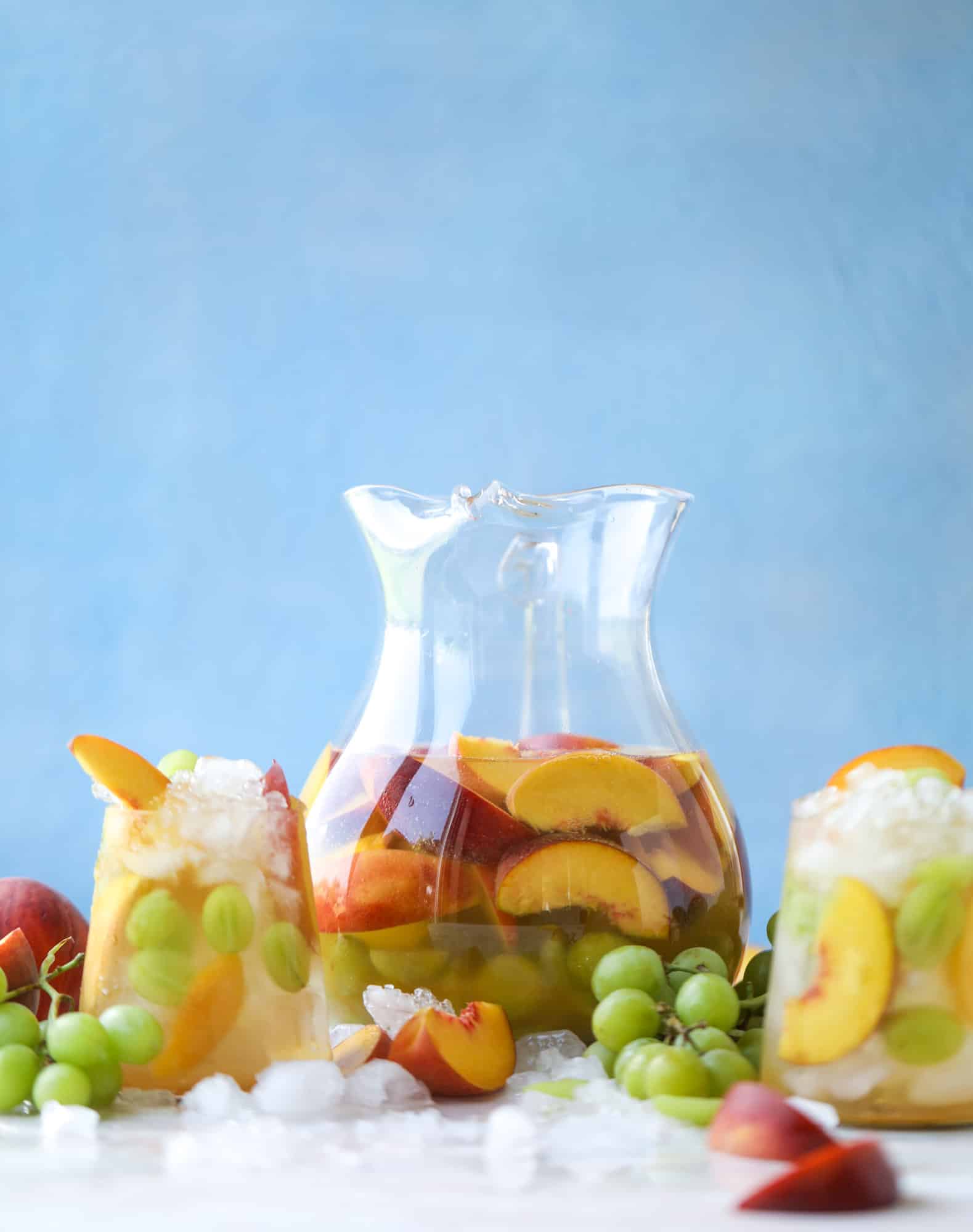 This pinot grigio sangria is absolutely perfect for summer, complete with peach nectar, fresh and frozen peach slices, brandy and bubbles! Frozen green grapes add some chill without watering down the drink. It's perfect! I howsweeteats.com #pinot #grigio #peach #sangria #cocktails #punch #summer #wine