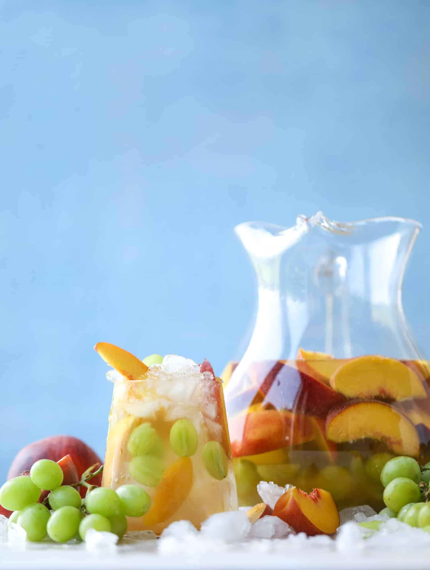 This pinot grigio sangria is absolutely perfect for summer, complete with peach nectar, fresh and frozen peach slices, brandy and bubbles! Frozen green grapes add some chill without watering down the drink. It's perfect! I howsweeteats.com #pinot #grigio #peach #sangria #cocktails #punch #summer #wine