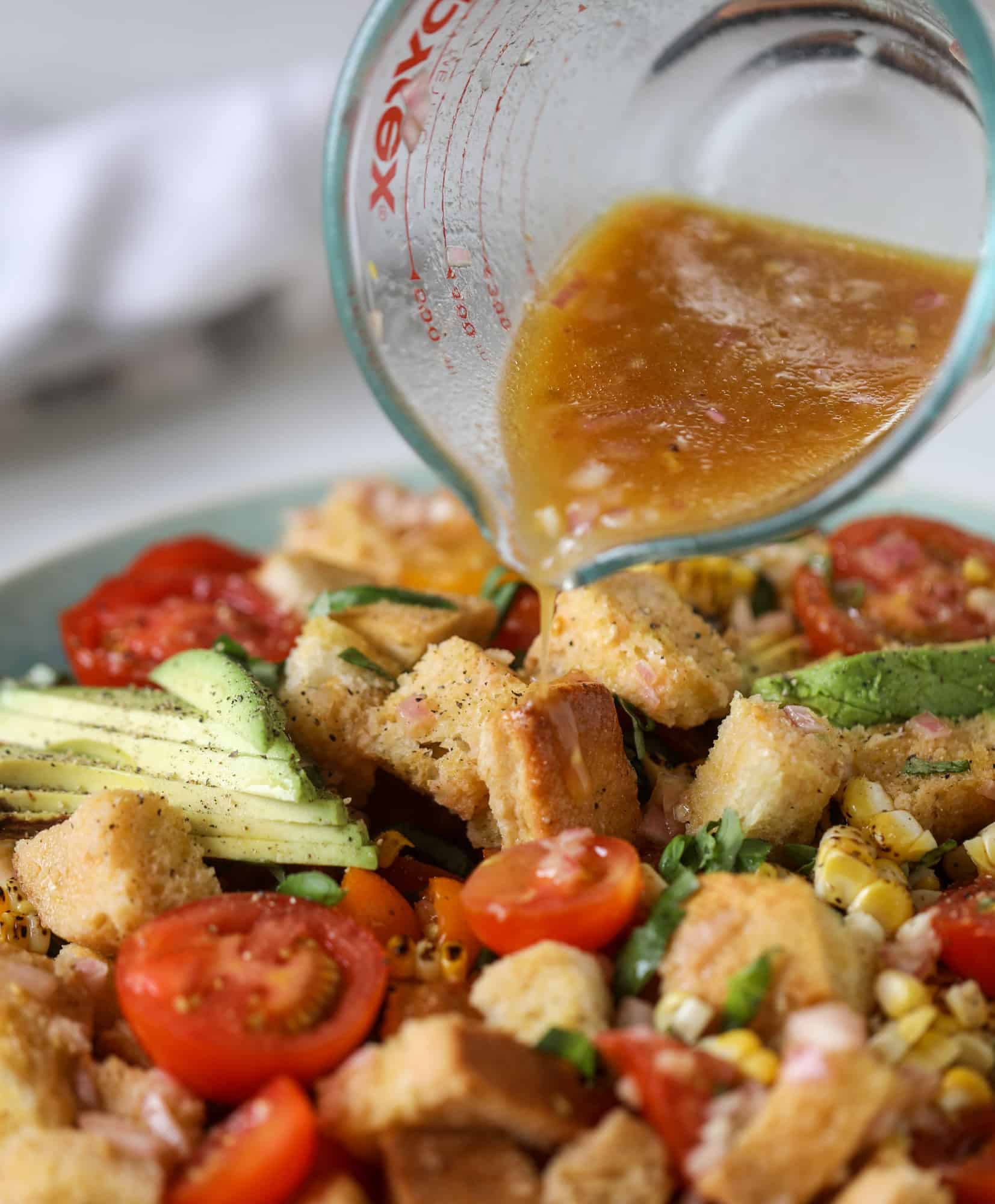 This is the perfect tomato panzanella salad! It's full of juicy, bursting, sweet tomatoes, toasted sourdough bread cubes, fresh herbs, grilled corn, sliced avocado and an incredible homemade dressing that blankets everything in deliciousness. SO good. I howsweeteats.com #panzanella #salad #tomato #basil #summer #corn #avocado #healthy #recipes