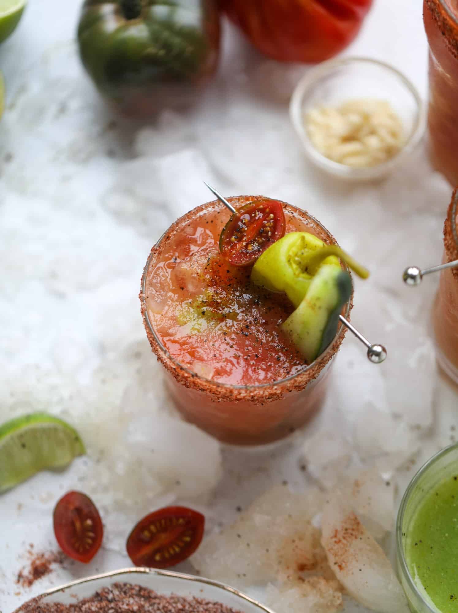 This bloody mary recipe is made with fresh heirloom tomatoes - the gems of summer! The colors swirl together to create a stunning drinking that is loaded with smoky, spicy flavor. Top with your favorite snacks foe the perfect brunch! I howsweeteats.com #bloody #mary #recipe #best #heirloom #tomatoes #cocktail