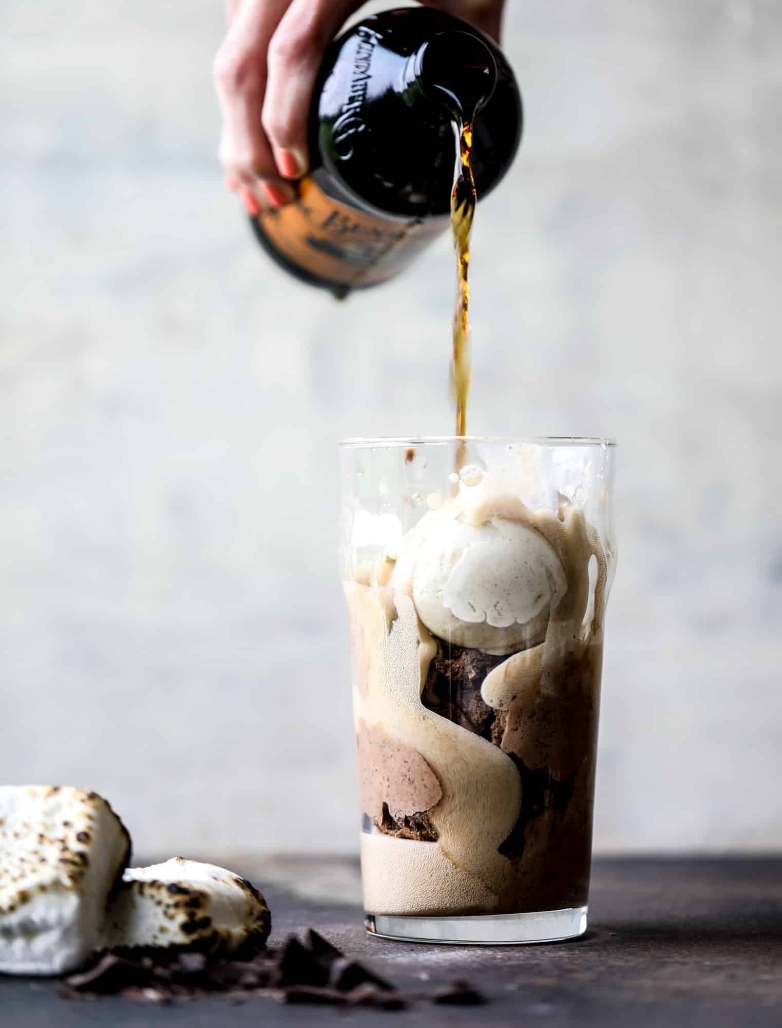 This is the most perfect root beer float, complete with both chocolate and vanilla ice creams. Topped with a smoky s'more, a chocolate fudge rim and a sprinkle of graham cracker crumbs take this super fun drink over the top! I howsweeteats.com #root #beer #float #summer #s'mores #drinks