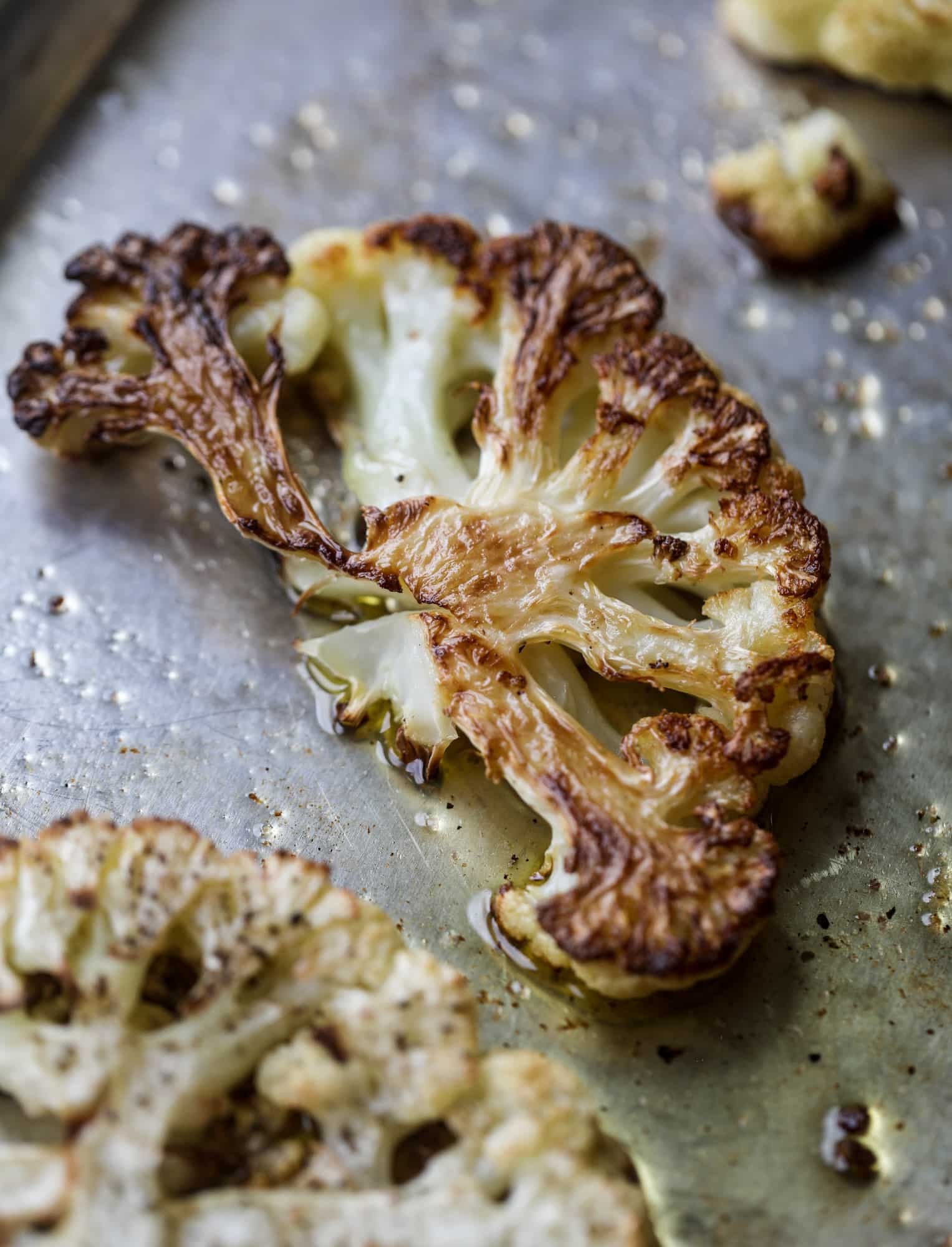 This roasted cauliflower with hummus, olives and feta is super flavorful and a wonderful meal, side dish or snack. Flavorful roasted cauliflower, creamy hummus, briney olives and tangy feta come together to make a major taste explosion. I howsweeteats.com #roasted #cauliflower #hummus #olives #feta