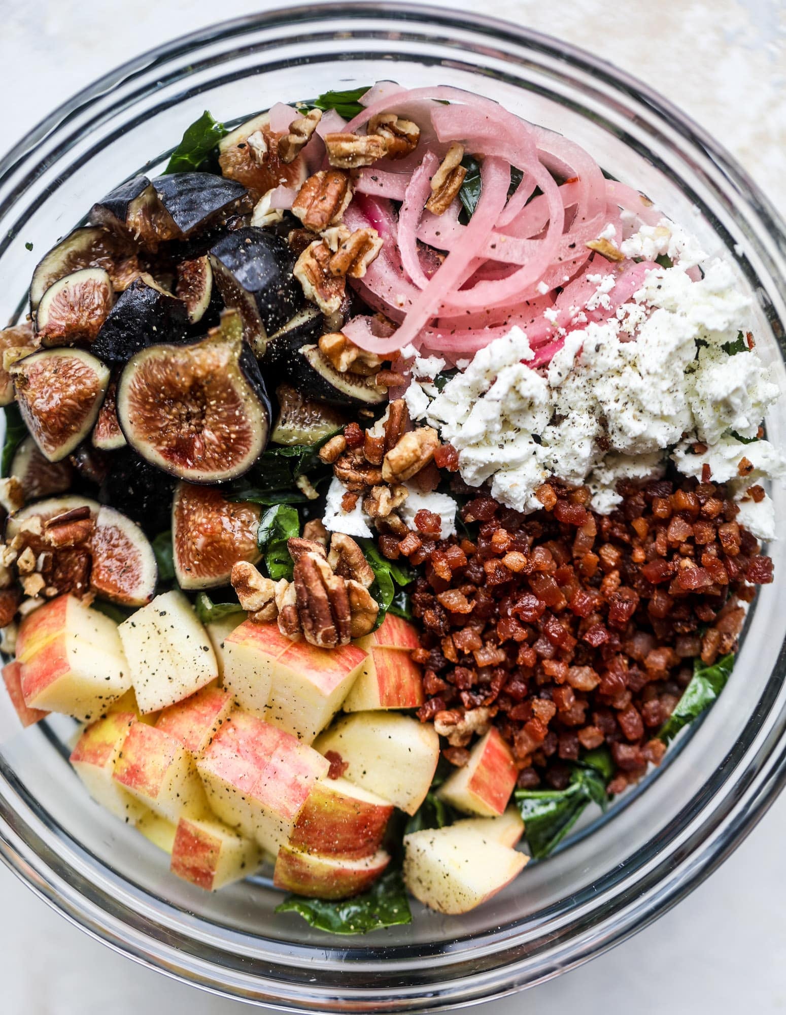 This fall kale salad is perfect for the season and full of so much delicious flavor! Shredded kale, honeycrisp apple, fresh figs, pancetta, pickled onions, pecans and goat cheese come together with a maple cider vinaigrette for salad heaven. I howsweeteats.com #fall #kale #salad #apples #figs #pecans