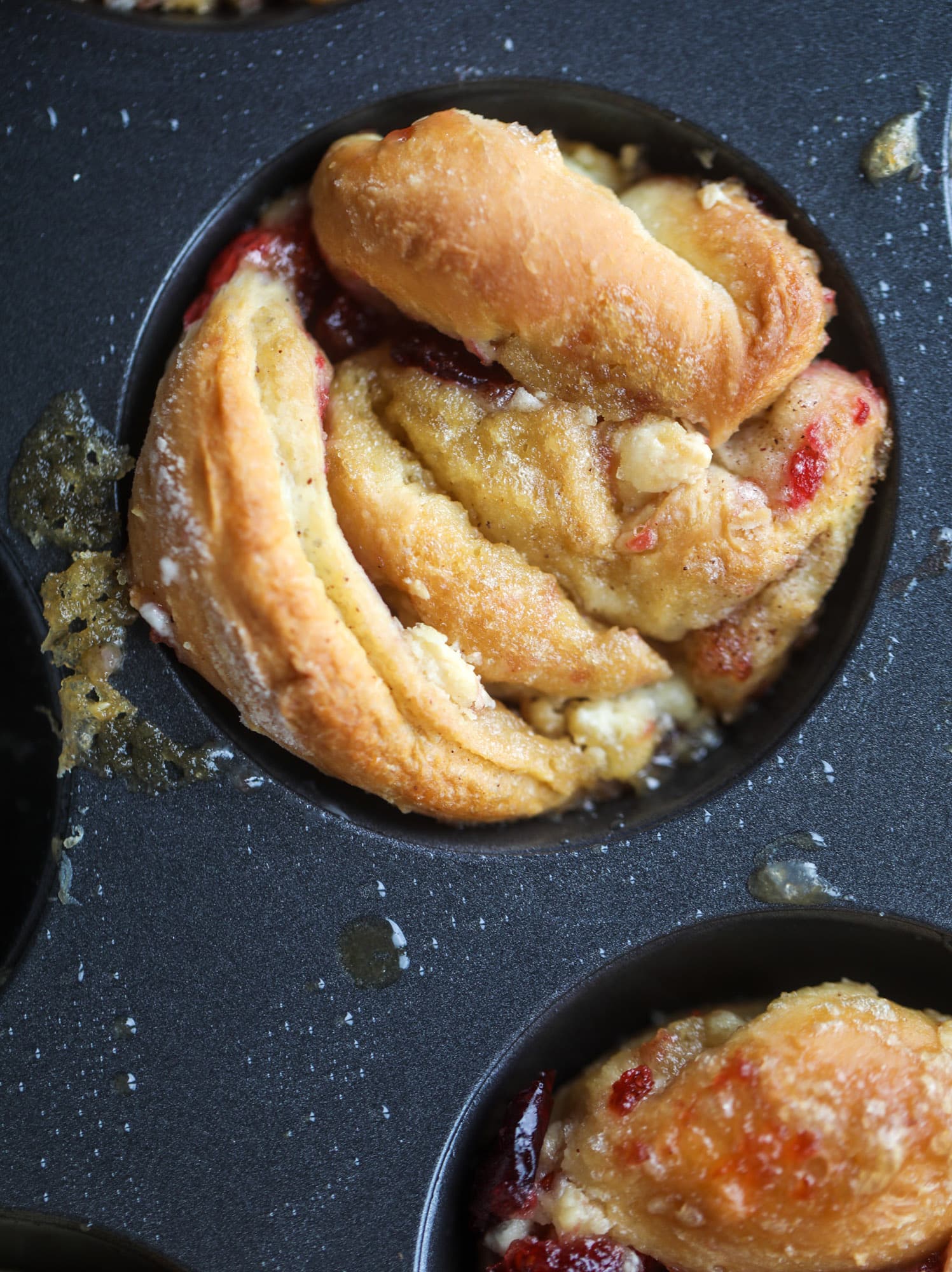 These white chocolate cranberry sticky buns are what holiday dreams are made of! Made in a muffin tin with fresh cranberries and creamy white chocolate, they are drizzled with cranberry caramel too! Dreamy! I howsweeteats.com #sticky #buns