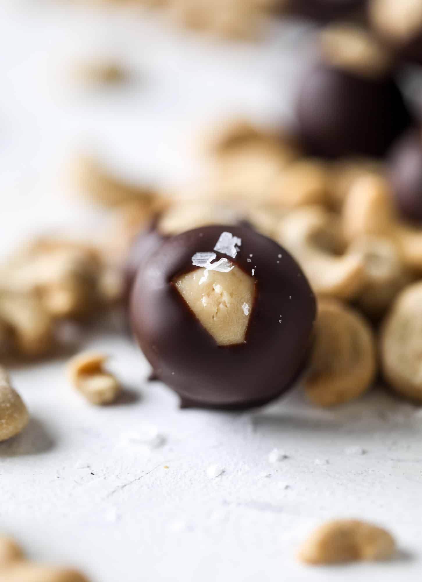 These cashew butter buckeyes are a fun and modern twist on the traditional buckeye recipe! Creamy cashew butter makes a delicious, rich dough and then it's coated in chocolate and sprinkled with sea salt. Delicious! I howsweeteats.com #cashewbutter #buckeyes