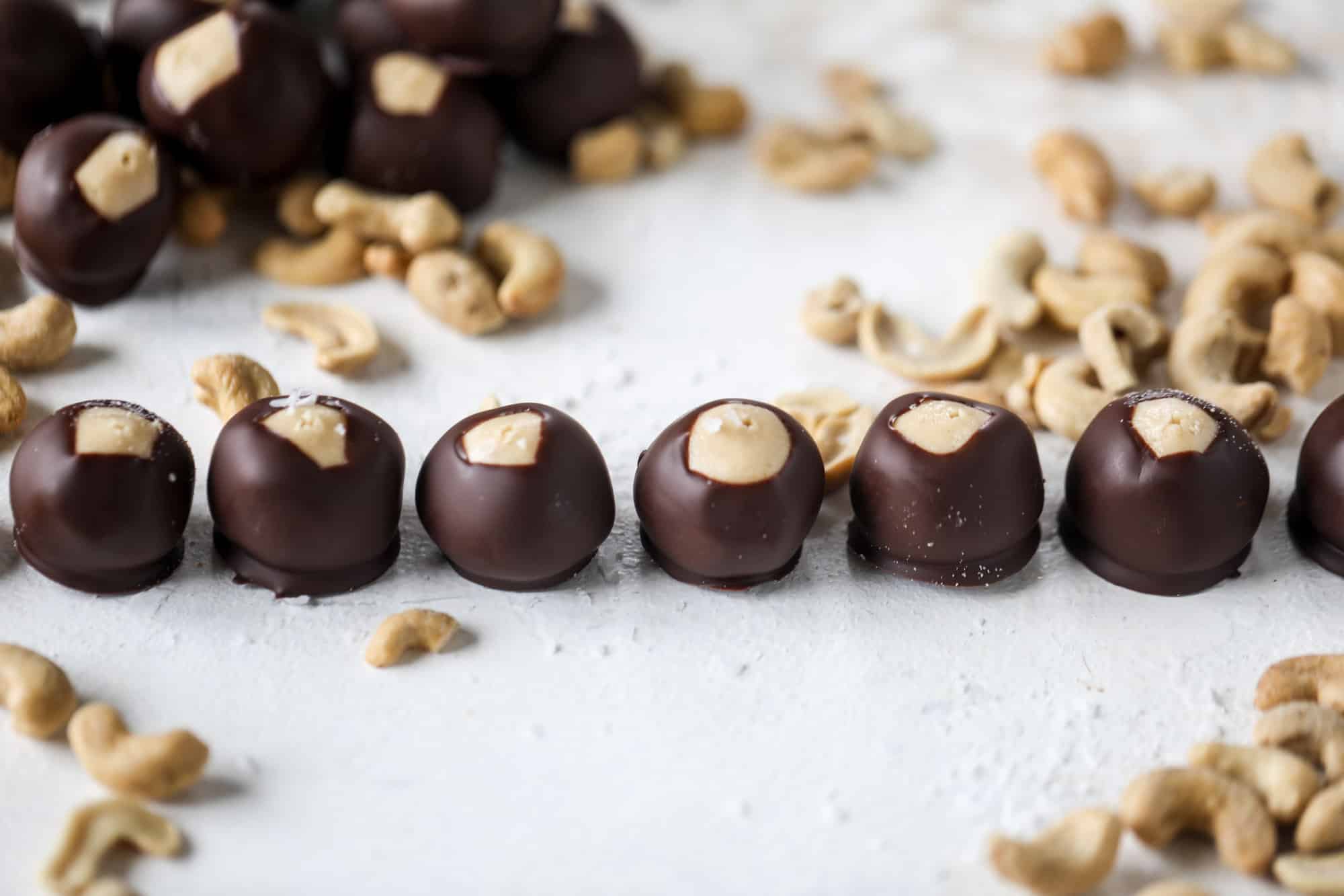 These cashew butter buckeyes are a fun and modern twist on the traditional buckeye recipe! Creamy cashew butter makes a delicious, rich dough and then it's coated in chocolate and sprinkled with sea salt. Delicious! I howsweeteats.com #cashewbutter #buckeyes