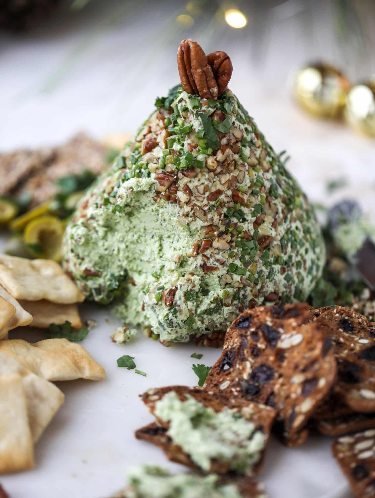 This green goddess cheese ball is the perfect party snack! You can make it ahead of time and shape it into a cute tree for a festive look. Serve it with crispy crackers and pita chips! I howsweeteats.com #greengoddess #cheeseball