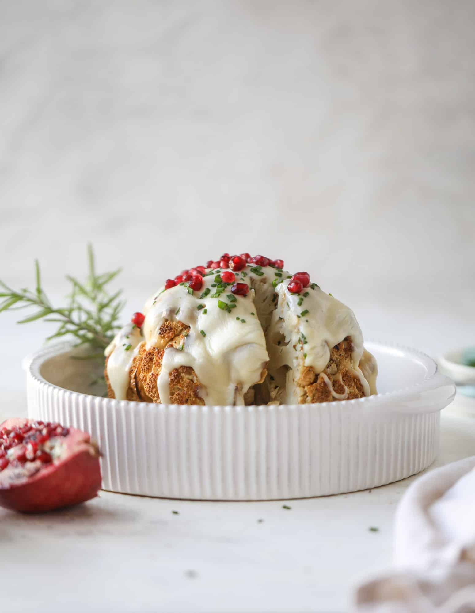 This whole roasted cauliflower fondue is roasted to toasty perfection and then covered in a fondue cheese sauce! Sprinkled with a festive garnish, it's the perfect appetizer or side dish for your dinner party, weeknight meal or movie night! I howsweeteats.com #wholeroasted #cauliflower