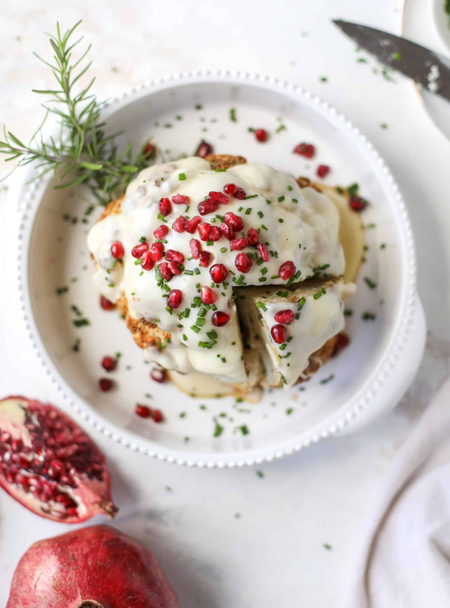 This whole roasted cauliflower fondue is roasted to toasty perfection and then covered in a fondue cheese sauce! Sprinkled with a festive garnish, it's the perfect appetizer or side dish for your dinner party, weeknight meal or movie night! I howsweeteats.com #wholeroasted #cauliflower