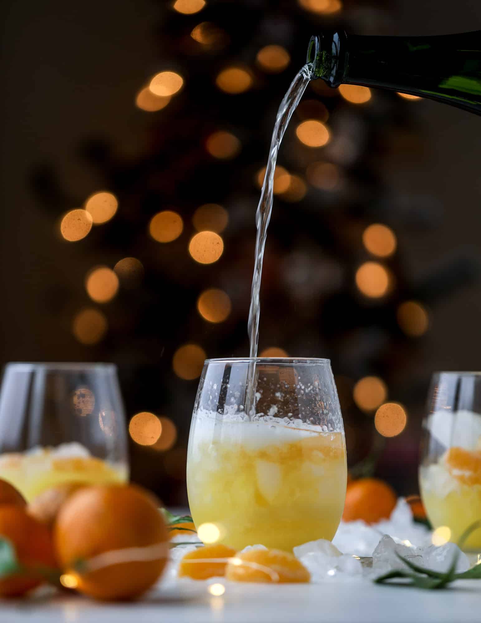 This satsuma cocktail is perfect for the holiday season and winter months when sweet satsumas are in season! This cocktail uses gin or vodka and is topped with champagne and garnished with a few satsuma wedges. Delicious! I howsweeteats.com #satsuma #cocktail