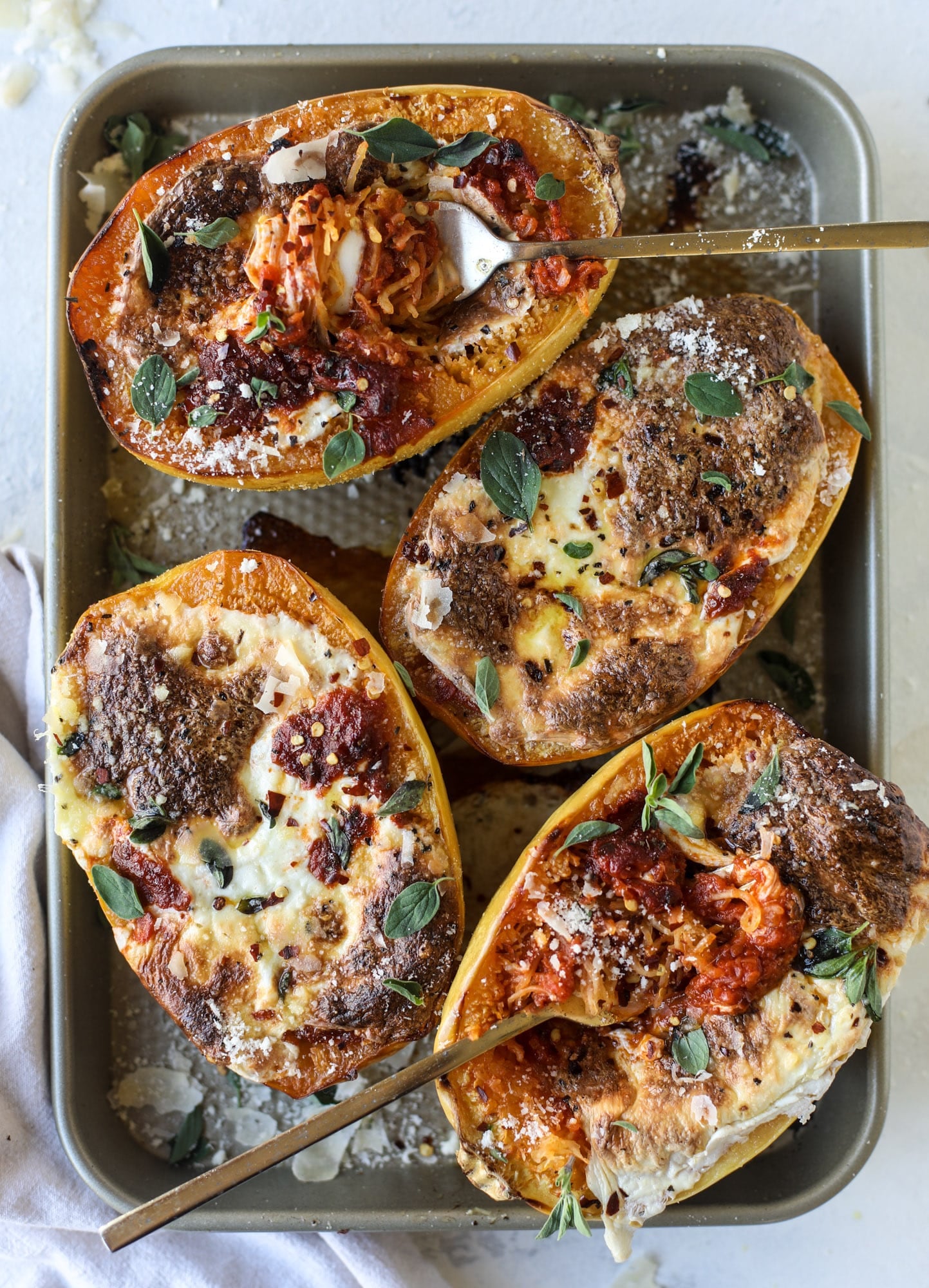 Spaghetti squash parmesan is a delicious weeknight meal! Topped with marinara or bolognese, melty cheese and fresh herbs, it's easy and delicious! I howsweeteats.com #spaghettisquash #parmesan