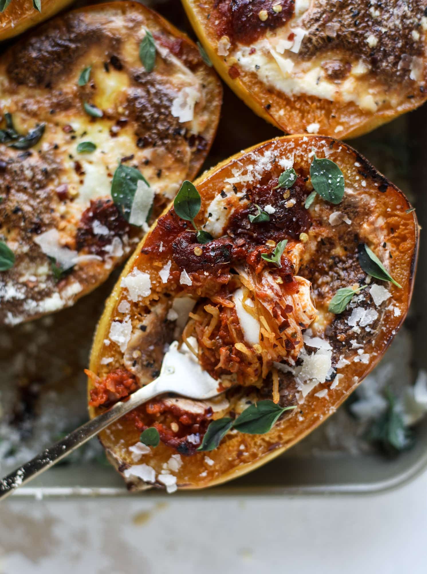 Spaghetti squash parmesan is a delicious weeknight meal! Topped with marinara or bolognese, melty cheese and fresh herbs, it's easy and delicious! I howsweeteats.com #spaghettisquash #parmesan