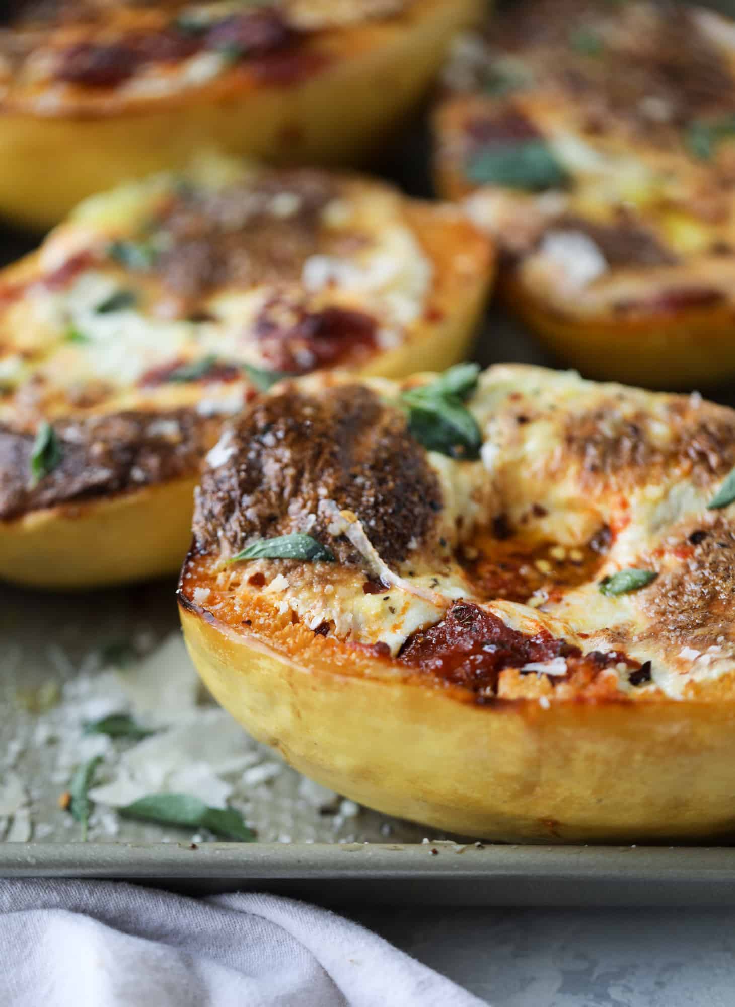 Spaghetti squash parmesan is a delicious weeknight meal! Topped with marinara or bolognese, melty cheese and fresh herbs, it's easy and delicious! I howsweeteats.com #spaghettisquash #parmesan