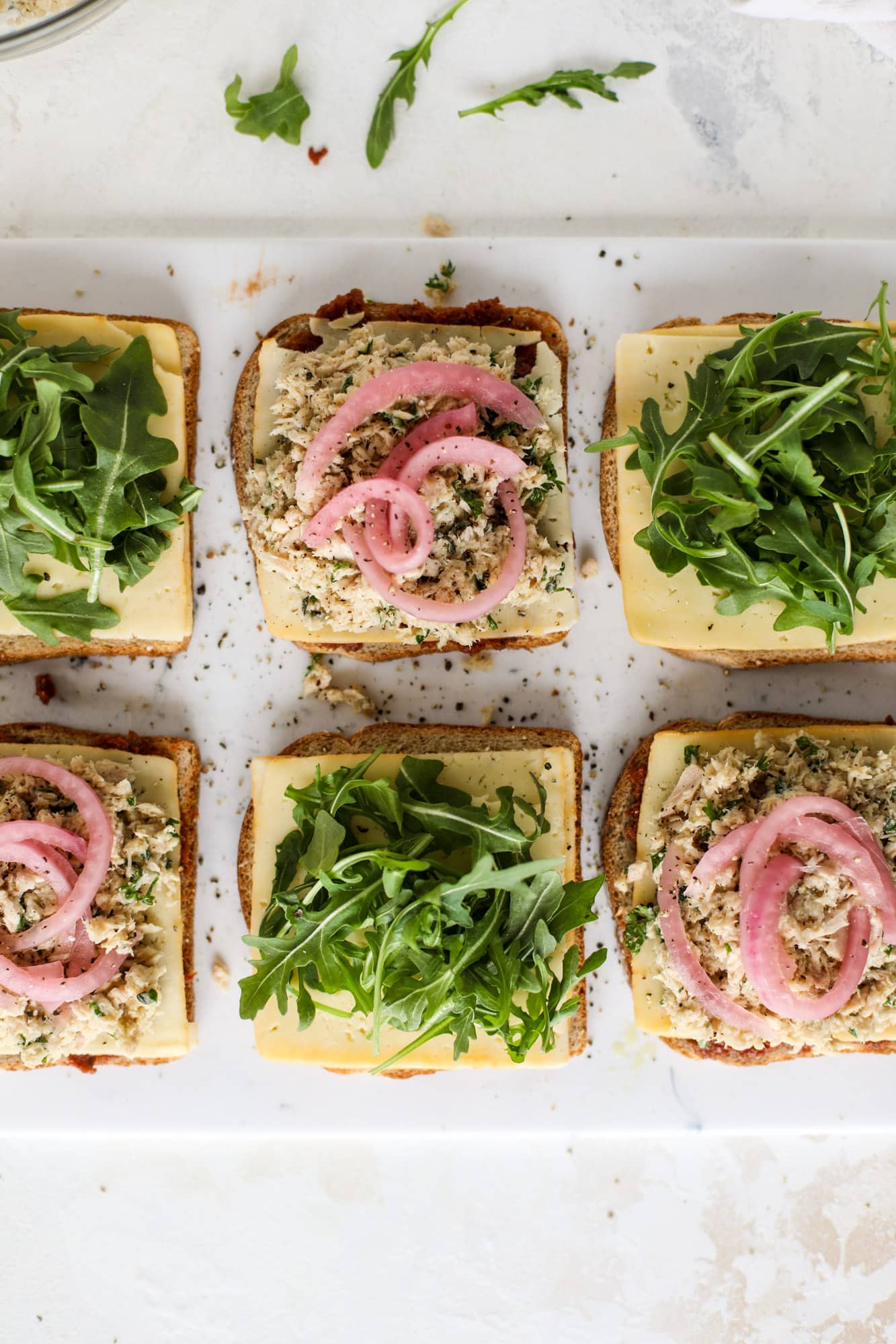 This tuscan tuna melt is a modern way to enjoy a tuna sandwich, with peppery arugula, melty cheese, pickled onions and sun dried tomato spread! I howsweeteats.com #tuna #melt