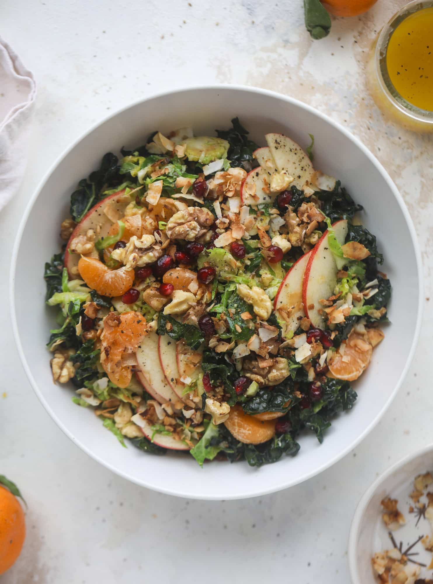 This winter crunch salad is loaded with tons of delicious, crunchy seasonal ingredients. A base of brussels sprouts and kale is topped with sliced apples, satsuma wedges, pomegranate arils, toasted walnuts and savory flaked coconut crunch. Delish! I howsweeteats.com #winter #salad