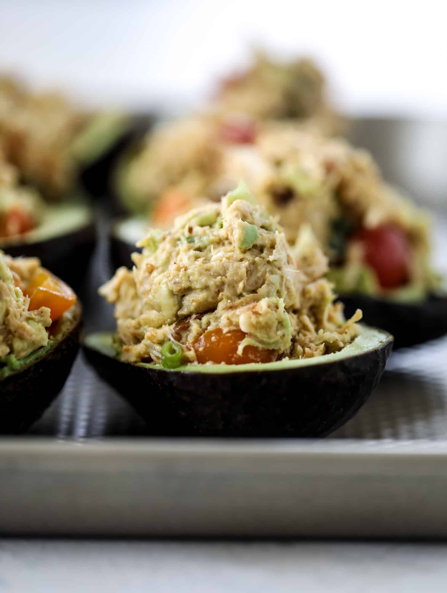 These baked avocados are stuffed with a cheesy chicken mixture and drizzled with sriracha yogurt sauce! Super delicious and an easy weeknight meal. I howsweeteats.com #baked #avocados