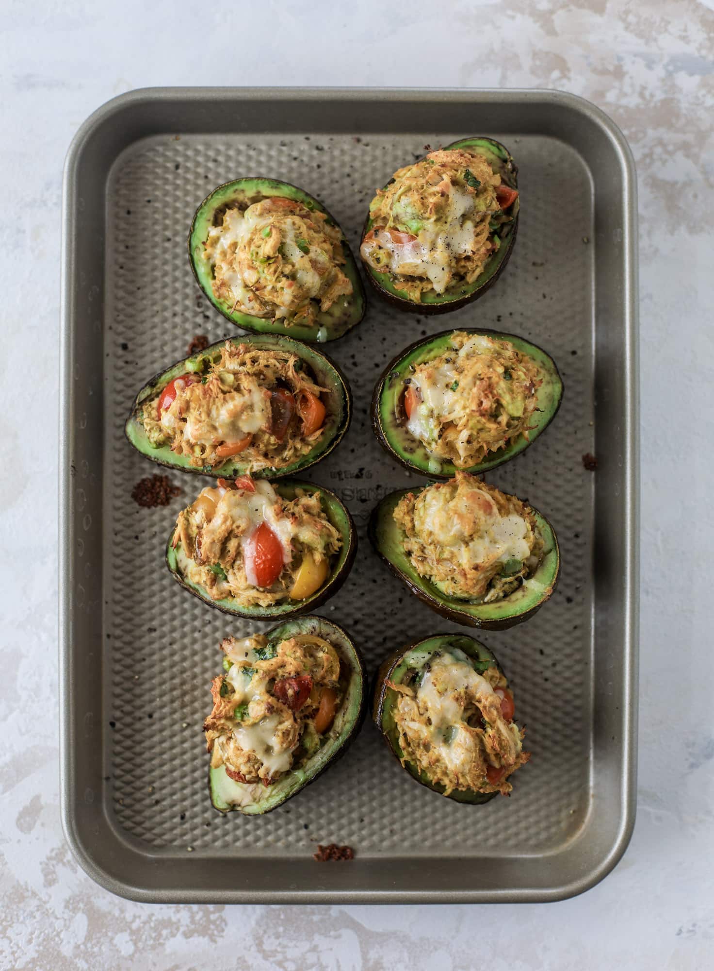 These baked avocados are stuffed with a cheesy chicken mixture and drizzled with sriracha yogurt sauce! Super delicious and an easy weeknight meal. I howsweeteats.com #baked #avocados