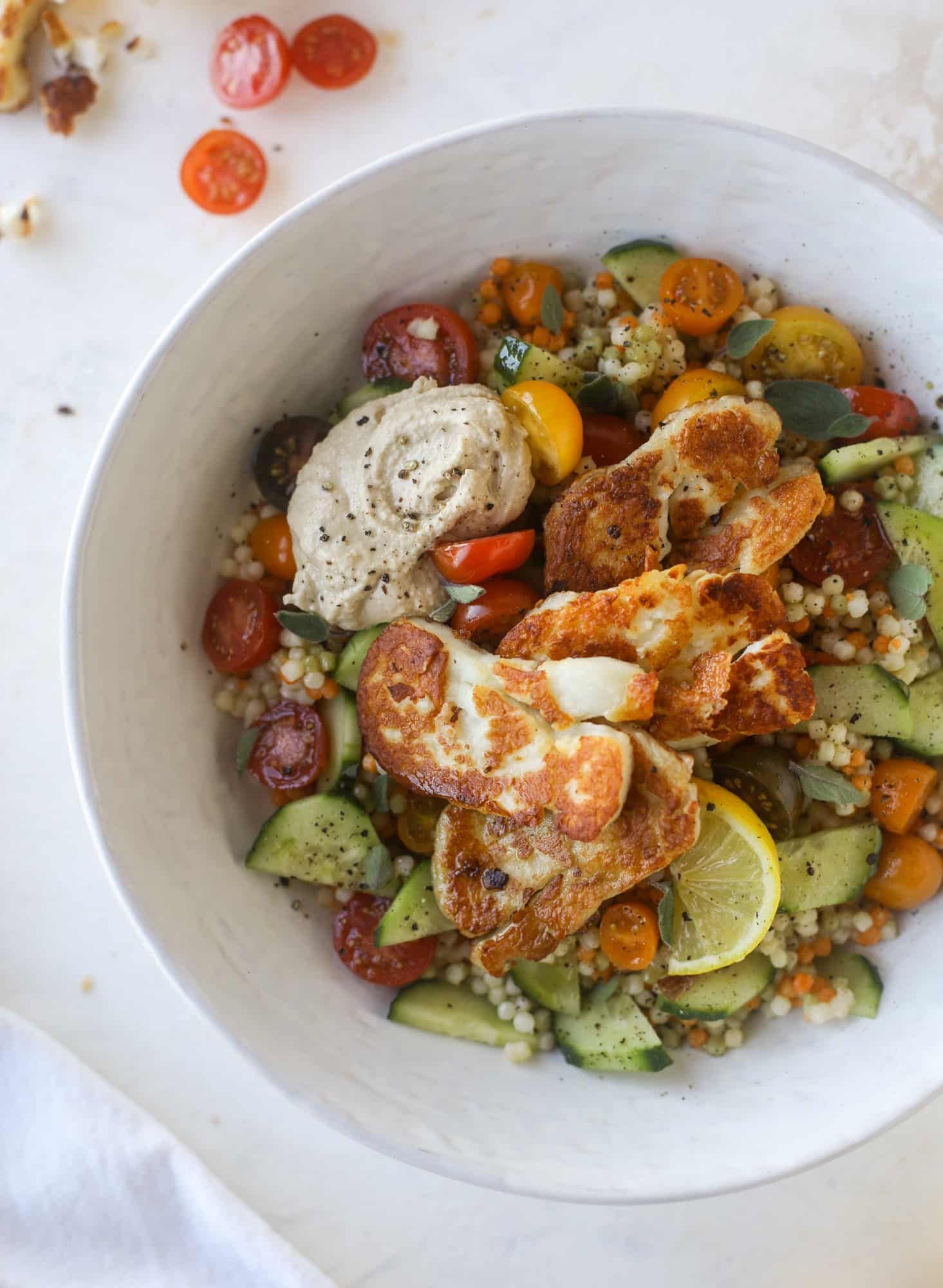 I am obsessed with these haulloumi hummus bowls for lunch or dinner. Couscous, veggies, crispy halloumi cheese and hummus with lots of lemon. Yum! I howsweeteats.com #halloumi #hummus