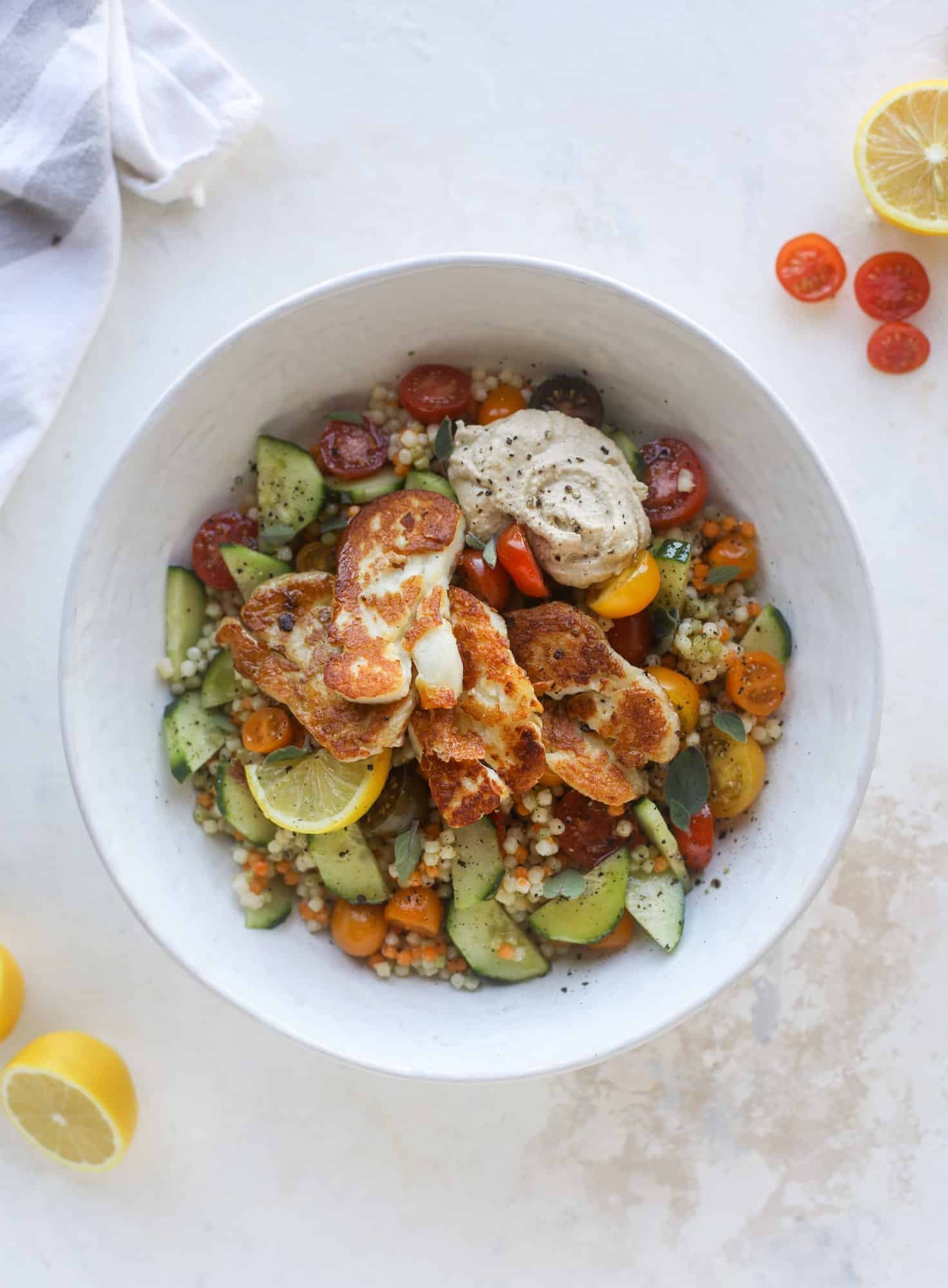 I am obsessed with these haulloumi hummus bowls for lunch or dinner. Couscous, veggies, crispy halloumi cheese and hummus with lots of lemon. Yum! I howsweeteats.com #halloumi #hummus