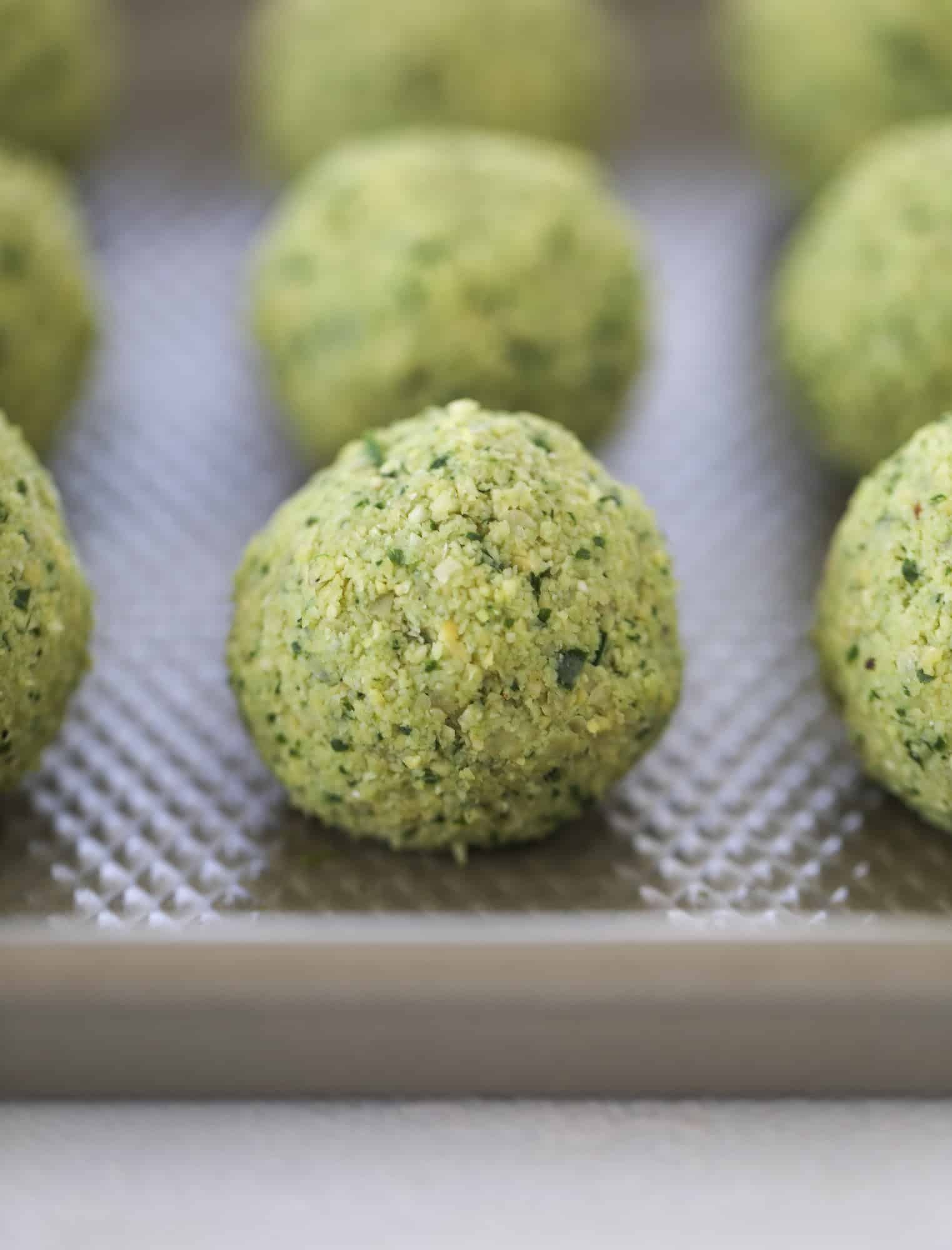 Green goddess falafel is hearty and flavorful, served over the creamiest cauliflower hummus, with tomatoes, olive, cucumbers and feta. Yum! I howsweeteats.com #falafel #cauliflowerhummus