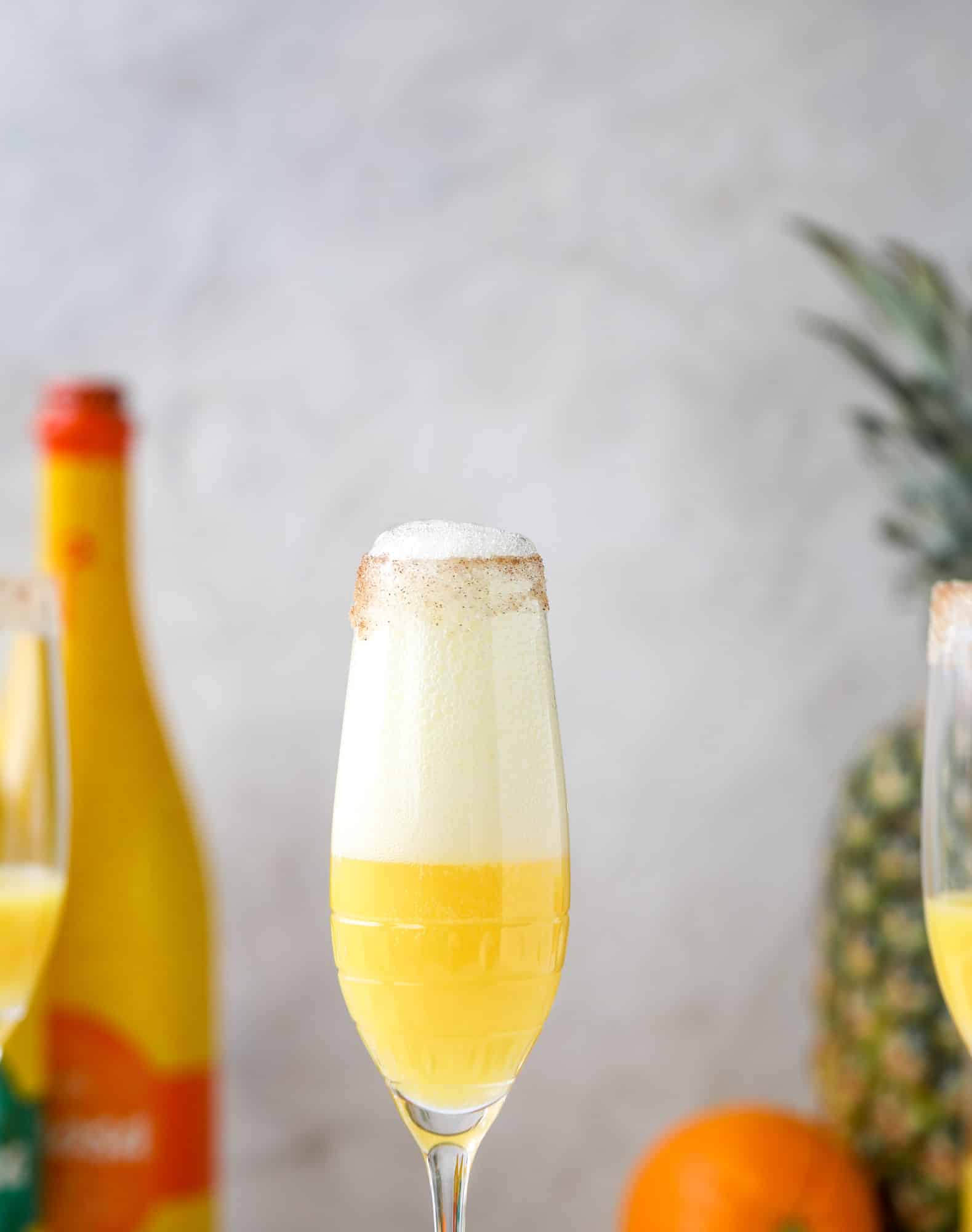 The hummingbird mimosa is a spin on the classic hummingbird cake: pineapple juice, orange juice, champagne and a cinnamon sugar rim! I howsweeteats.com #hummingbird #mimosa