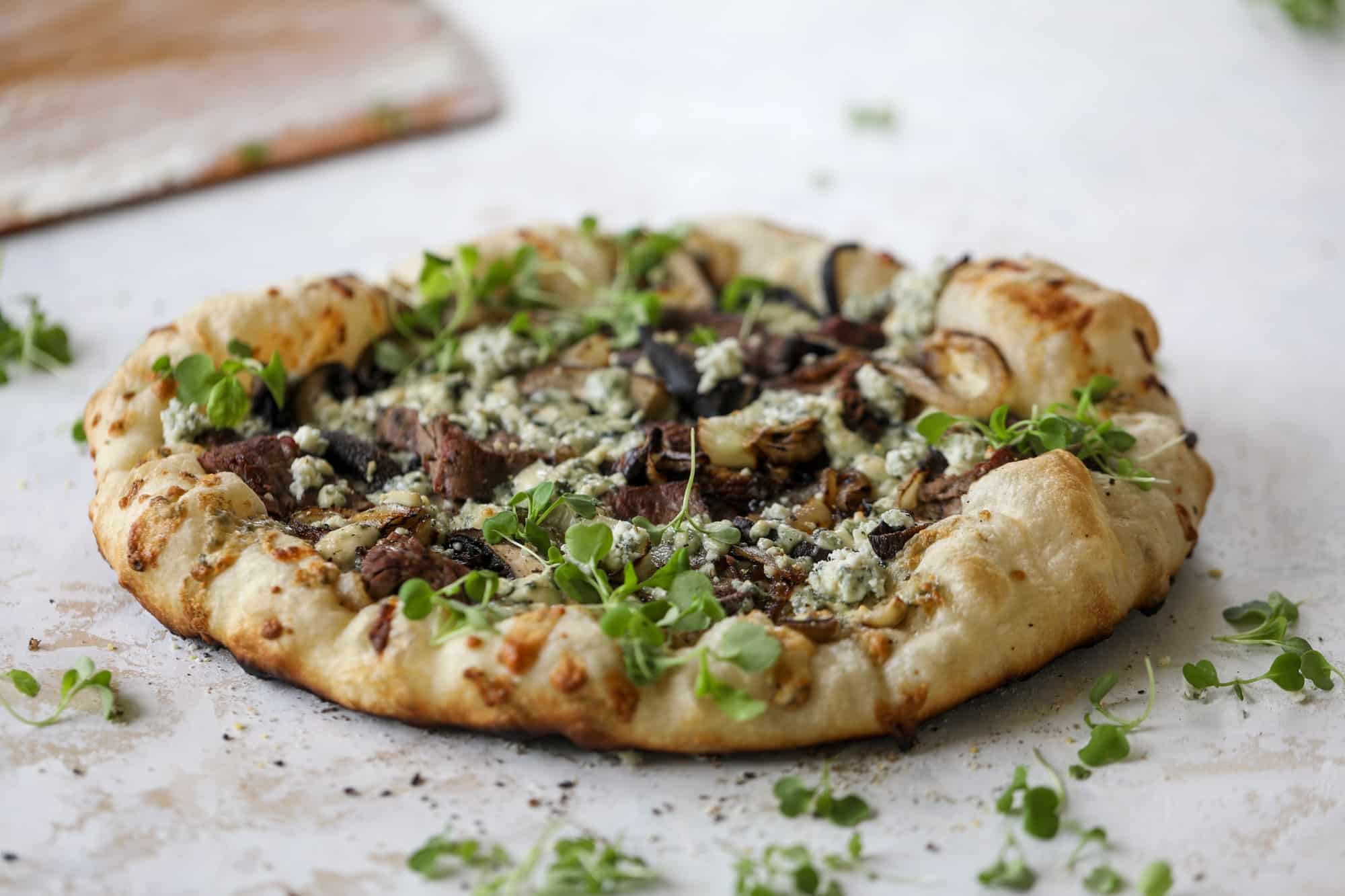 This grilled steakhouse pizza has all the amazing smoky flavors of your favorite steakhouse. Grilled onions, mushrooms and creamy gorgonzola finish it off.