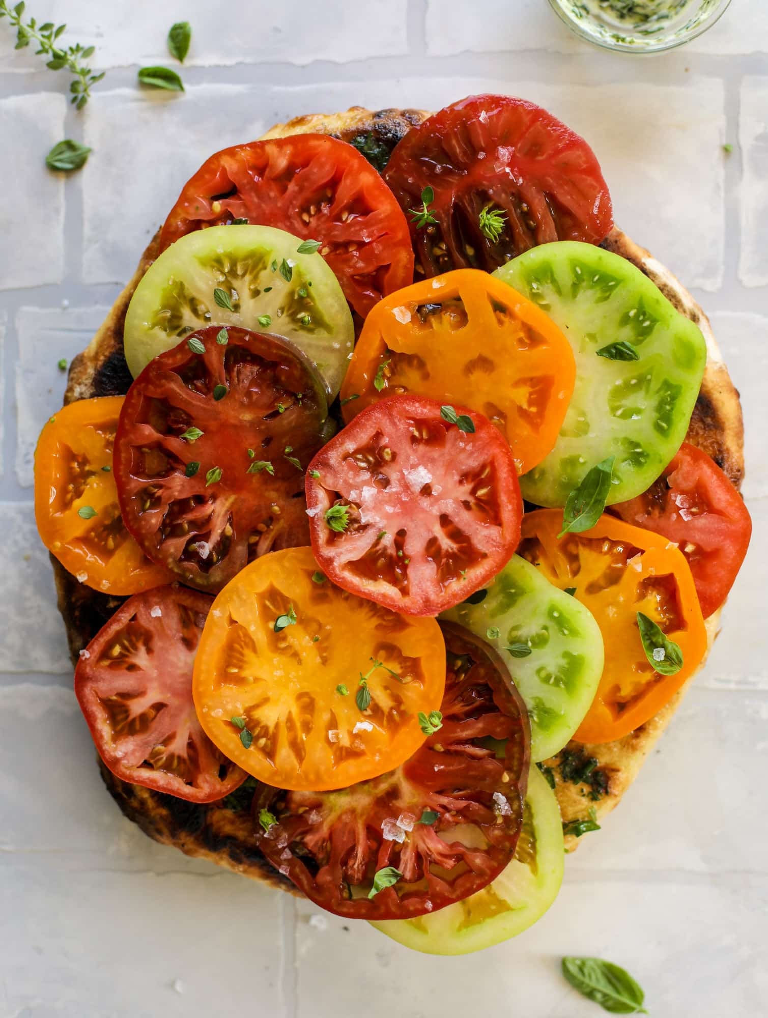 This heirloom tomato pizza starts with a grilled garlic herb butter crust! Melty herb butter and sliced fresh tomatoes top it off for a delicious bite!