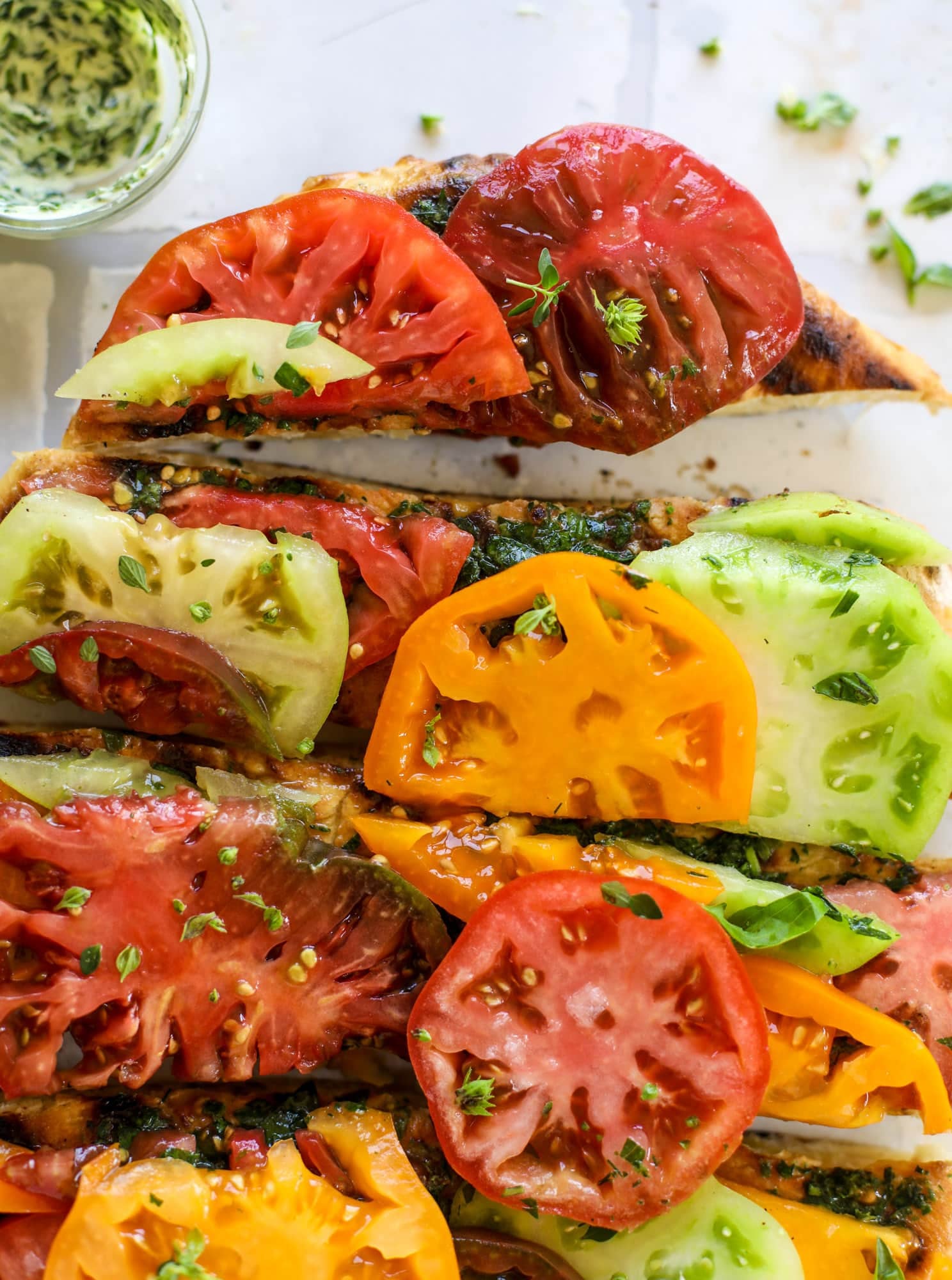 This heirloom tomato pizza starts with a grilled garlic herb butter crust! Melty herb butter and sliced fresh tomatoes top it off for a delicious bite!
