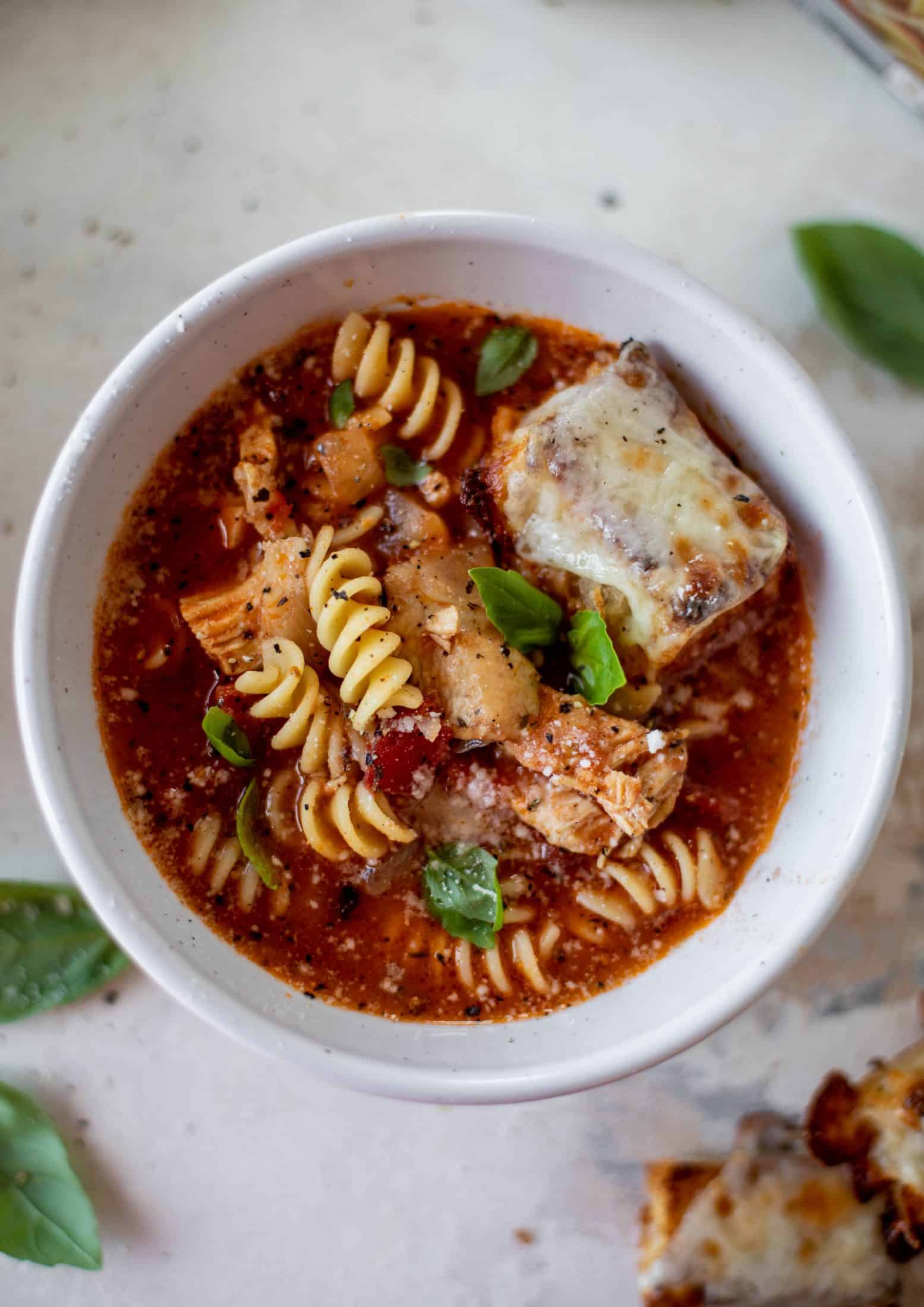 This chicken parmesan soup is ridiculously flavorful and so easy to make! Juicy chicken with pasta, fire roasted tomatoes and mozzarella croutons. Yum!