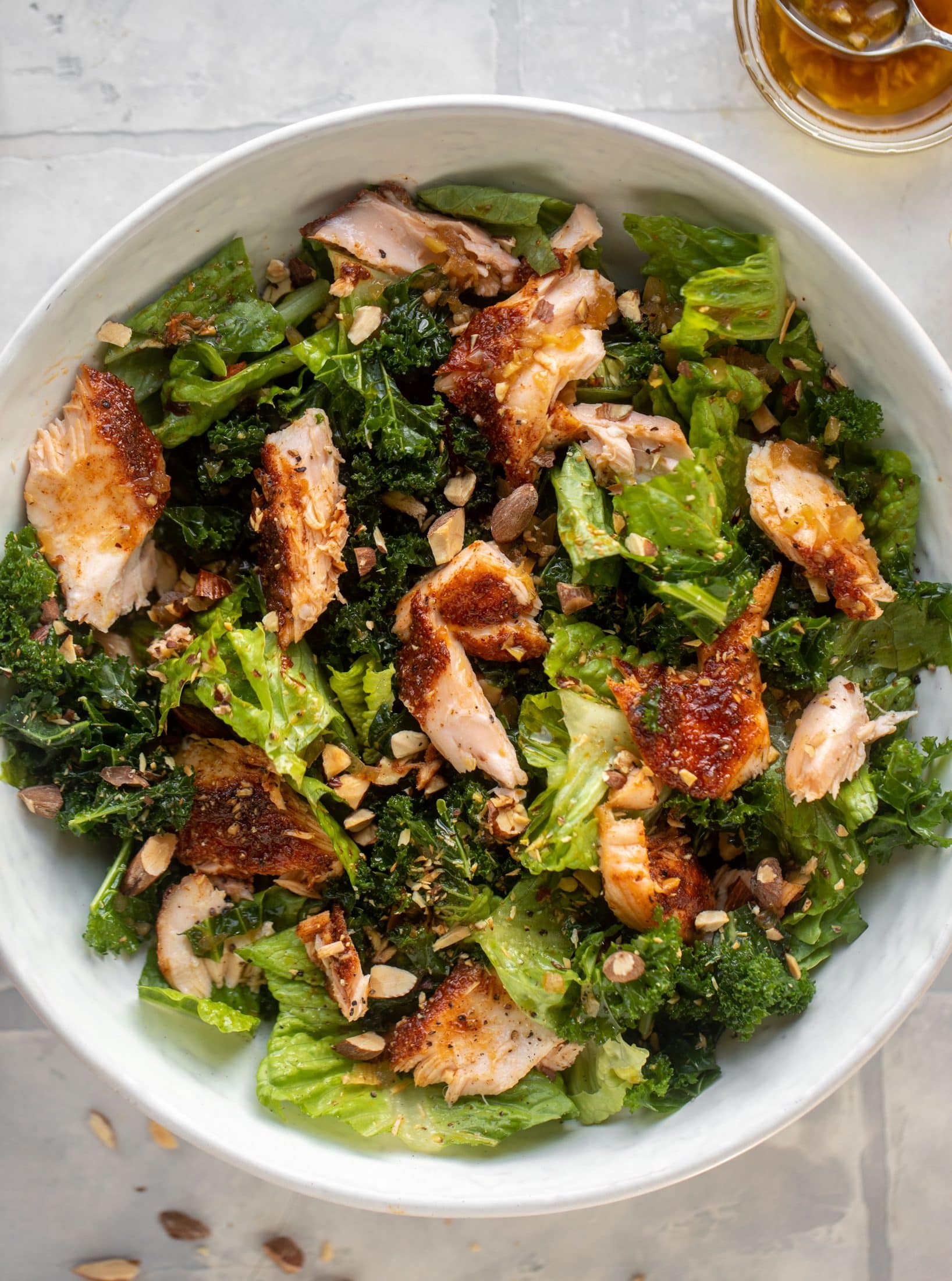 This ginger salmon salad has the flaky, flavorful roasted salmon on top of kale and romaine, drizzled with warm ginger vinaigrette.