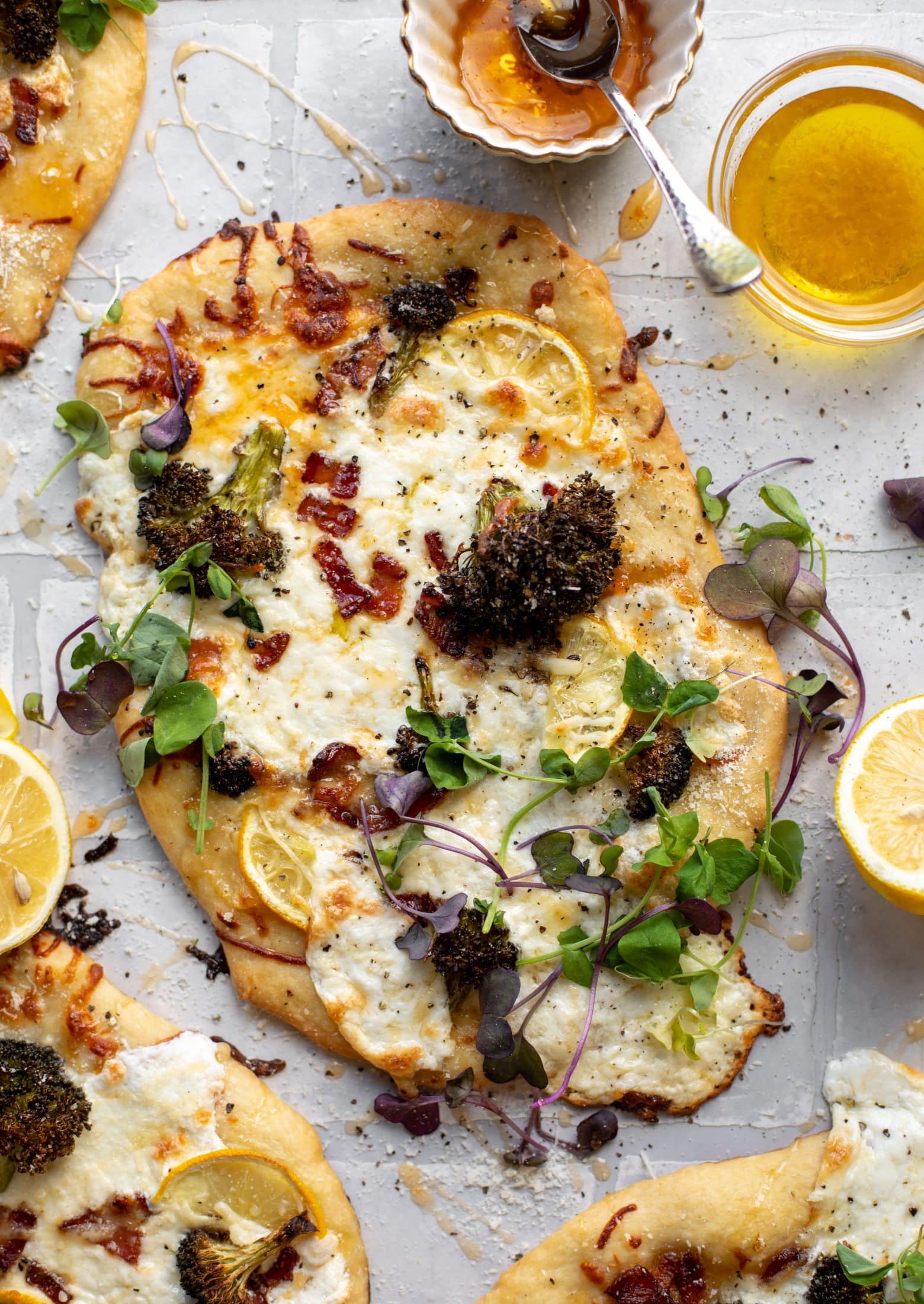 This cheesy lemon flatbread pizza is covered with burrata cheese, parmesan, roasted vegetables and hot honey. It's a flavor dream!