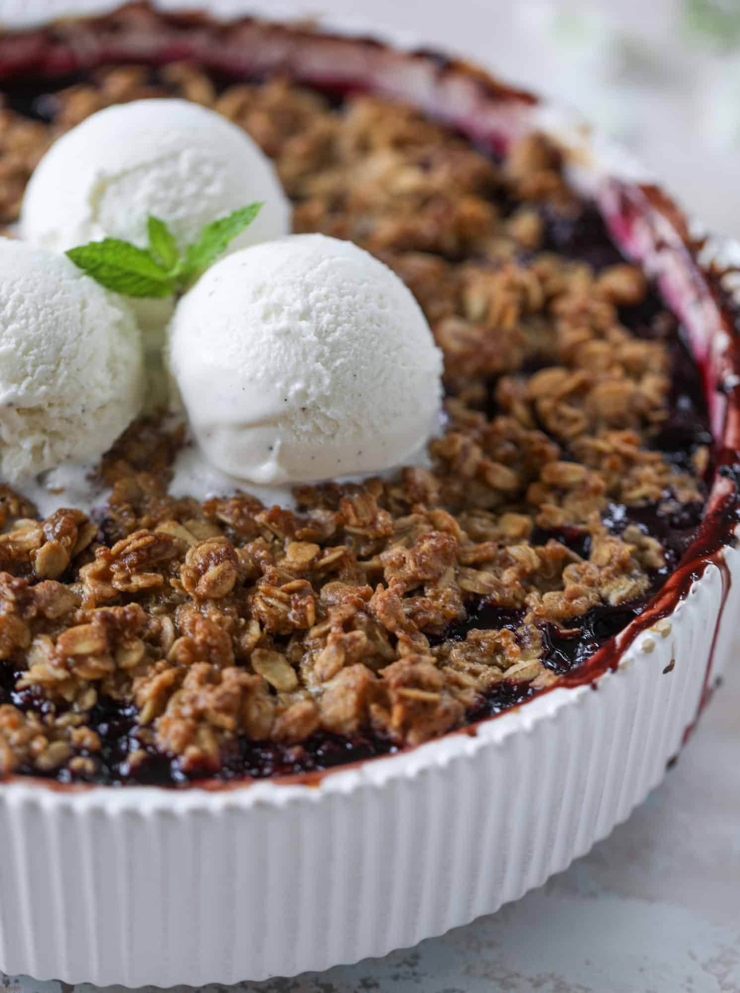 This blueberry crisp is warm and bursting with sweet and juicy fruit. It's topped with a quinoa oatmeal brown sugar topping and is the perfect dessert for summer. Served warm and topped with vanilla ice cream, it's just divine! I howsweeteats.com #blueberry #crisp #quinoa #oats #dessert #fruit