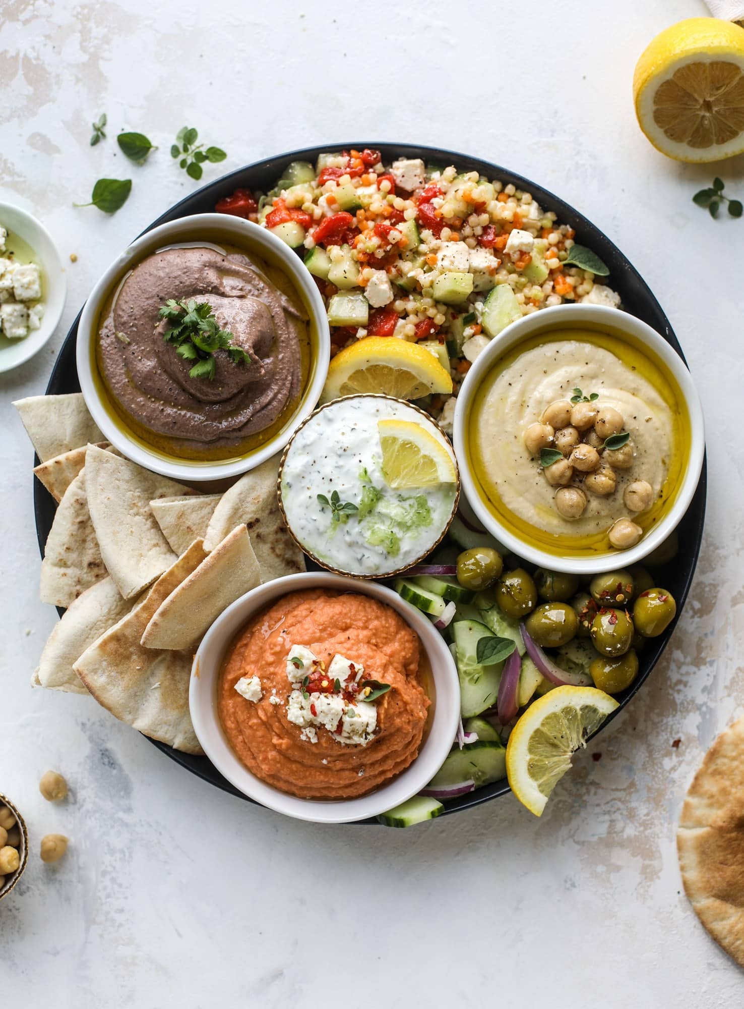 Here you can find out how to make the perfect hummus platter! This trio includes caramelized onion hummus, smoky black bean hummus and roasted red pepper white bean hummus, along with a couscous salad and quick tzatziki! I howsweeteats.com #hummus #platter #appetizer #snack #chickpeas #healthy #blackbeans #yogurt #tzatziki