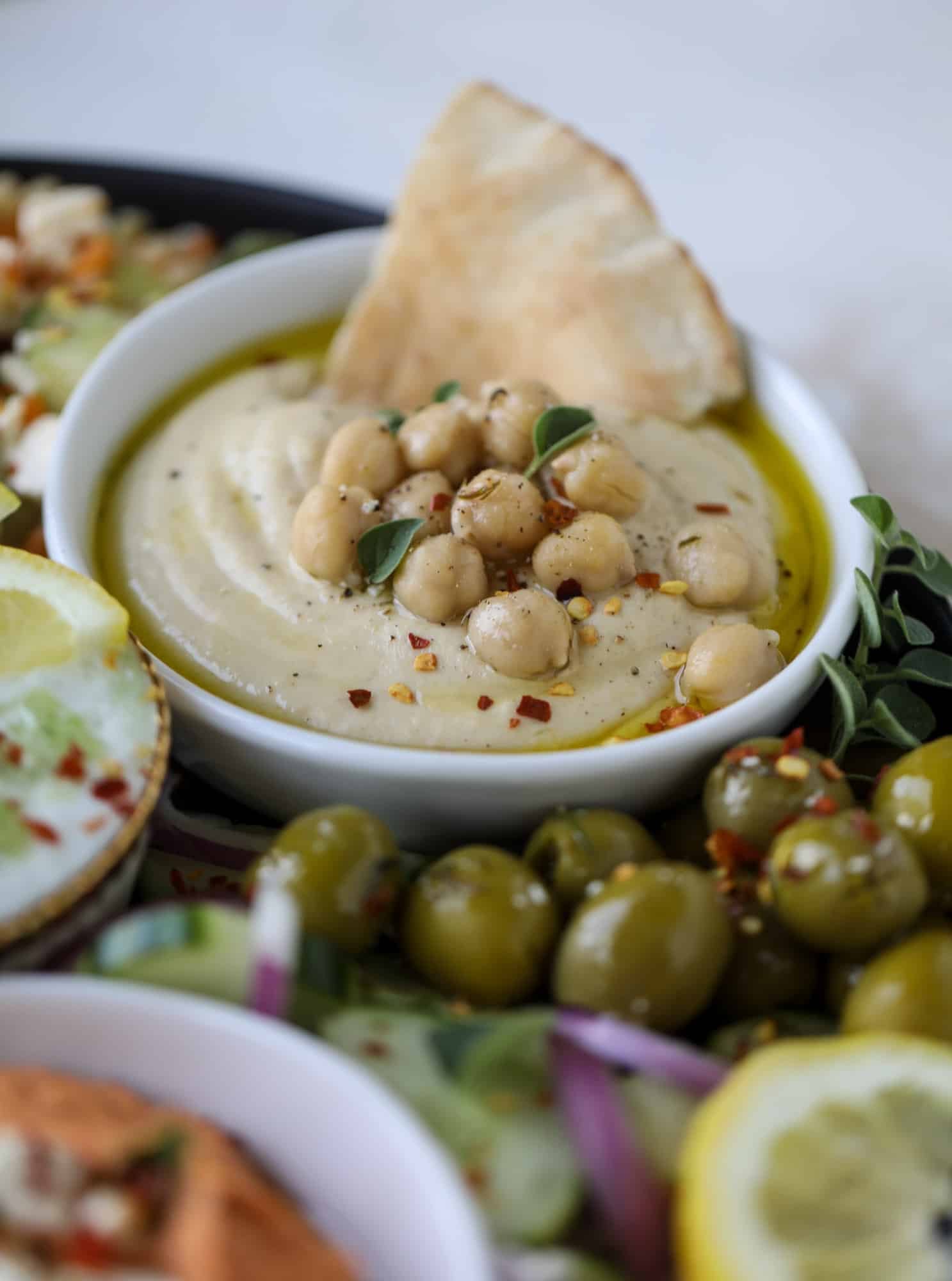 Here you can find out how to make the perfect hummus platter! This trio includes caramelized onion hummus, smoky black bean hummus and roasted red pepper white bean hummus, along with a couscous salad and quick tzatziki! I howsweeteats.com #hummus #platter #appetizer #snack #chickpeas #healthy #blackbeans #yogurt #tzatziki