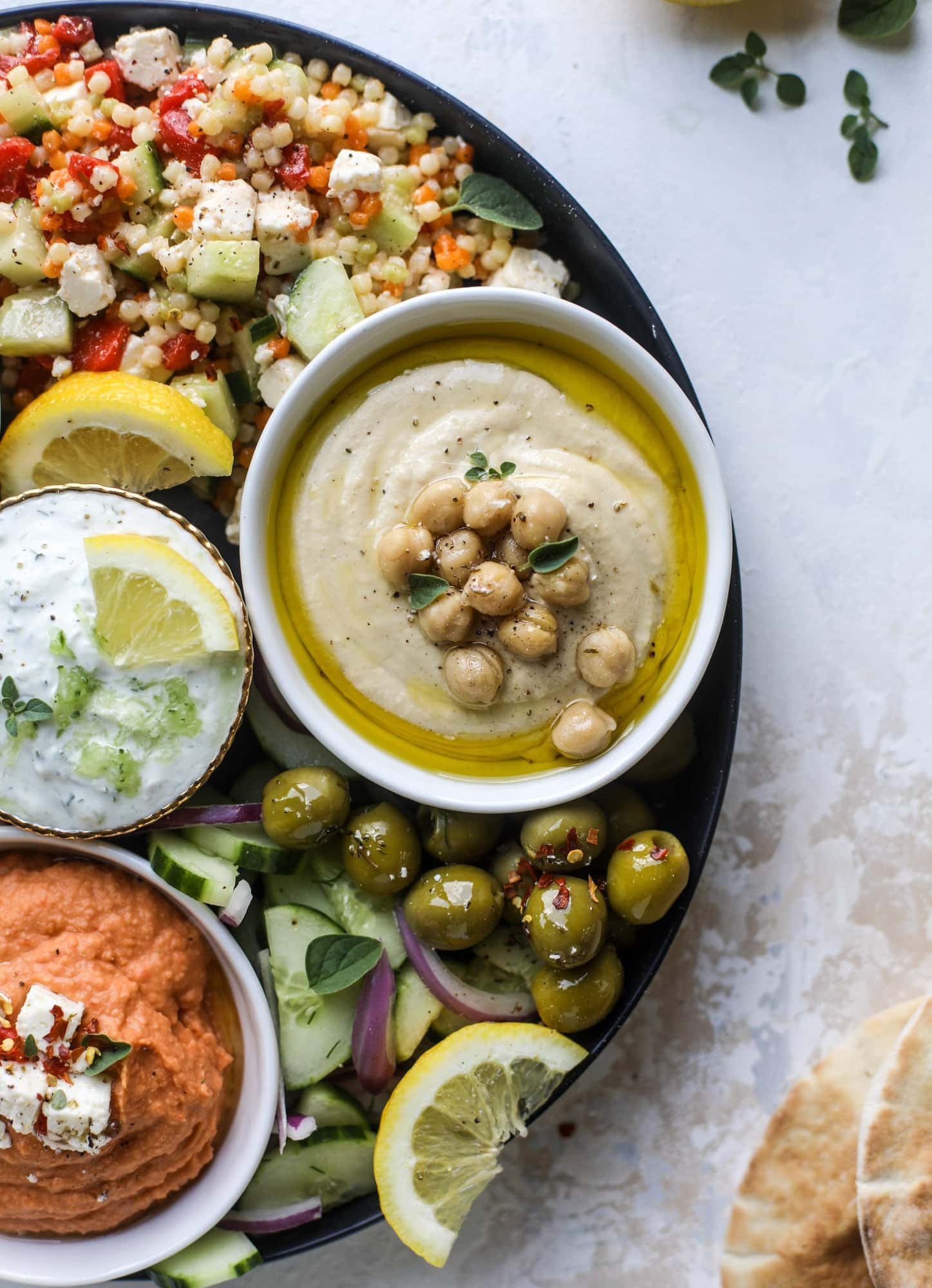 Here you can find out how to make the perfect hummus platter! This trio includes caramelized onion hummus, smoky black bean hummus and roasted red pepper white bean hummus, along with a couscous salad and quick tzatziki! I howsweeteats.com #hummus #platter #appetizer #snack #chickpeas #healthy #blackbeans #yogurt #tzatziki