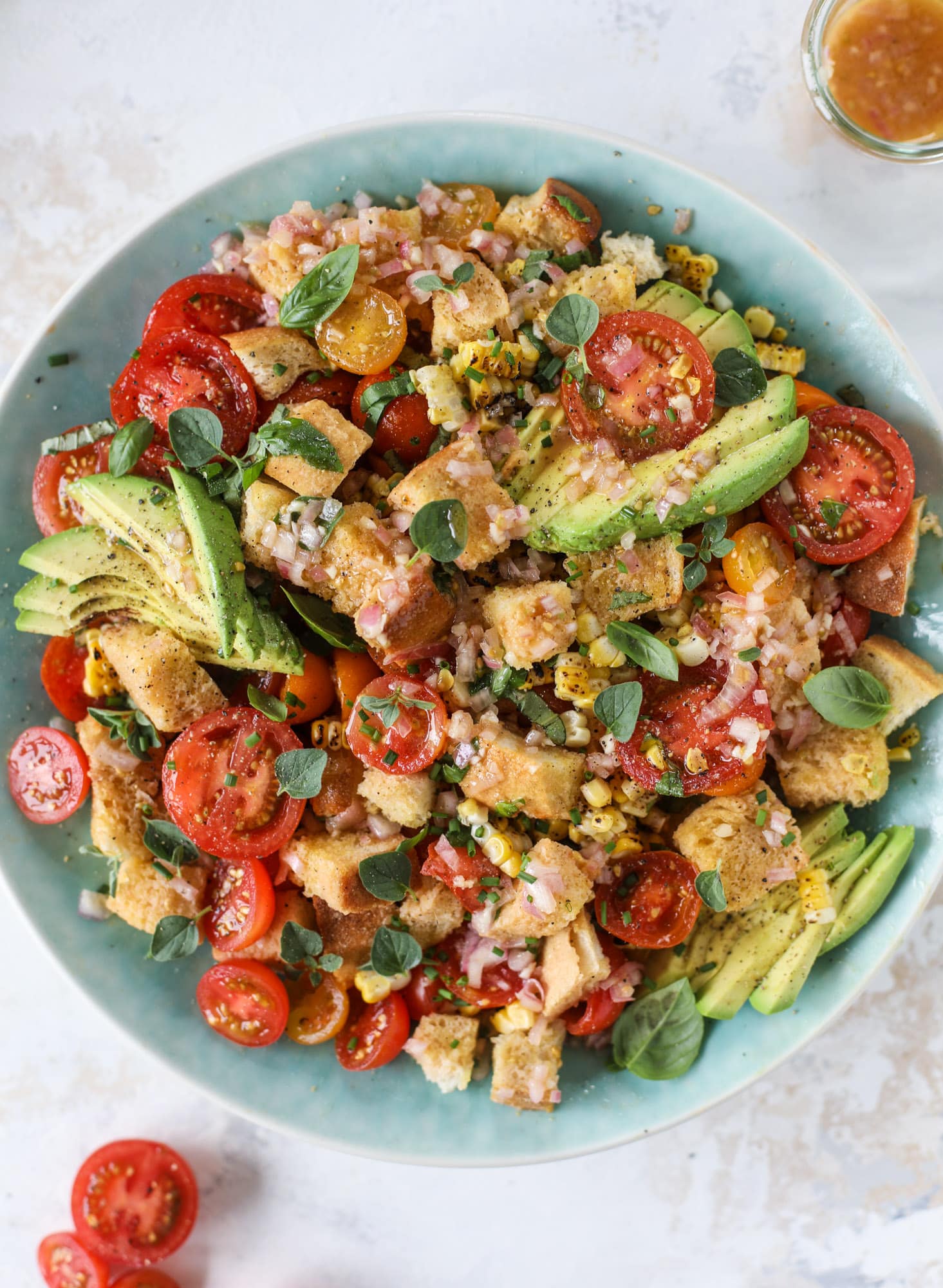 This is the perfect tomato panzanella salad! It's full of juicy, bursting, sweet tomatoes, toasted sourdough bread cubes, fresh herbs, grilled corn, sliced avocado and an incredible homemade dressing that blankets everything in deliciousness. SO good. I howsweeteats.com #panzanella #salad #tomato #basil #summer #corn #avocado #healthy #recipes