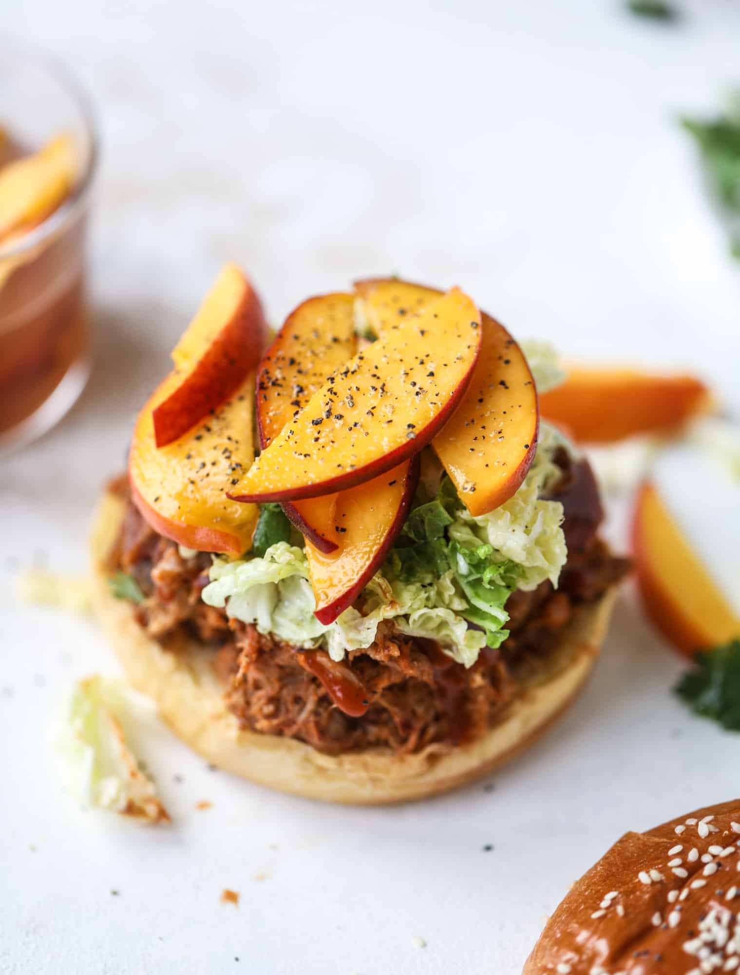 This chipotle pulled pork sandwich is spicy, sweet and saucy. Throw it on a bun or a plate and top it with the most delicious quick pickled peaches and napa cabbage slaw. Flavor and texture make this sandwich incredible! I howsweeteats.com #pulled #pork #chipotle #pickled #peaches #slaw #sandwiches #slow #cooker