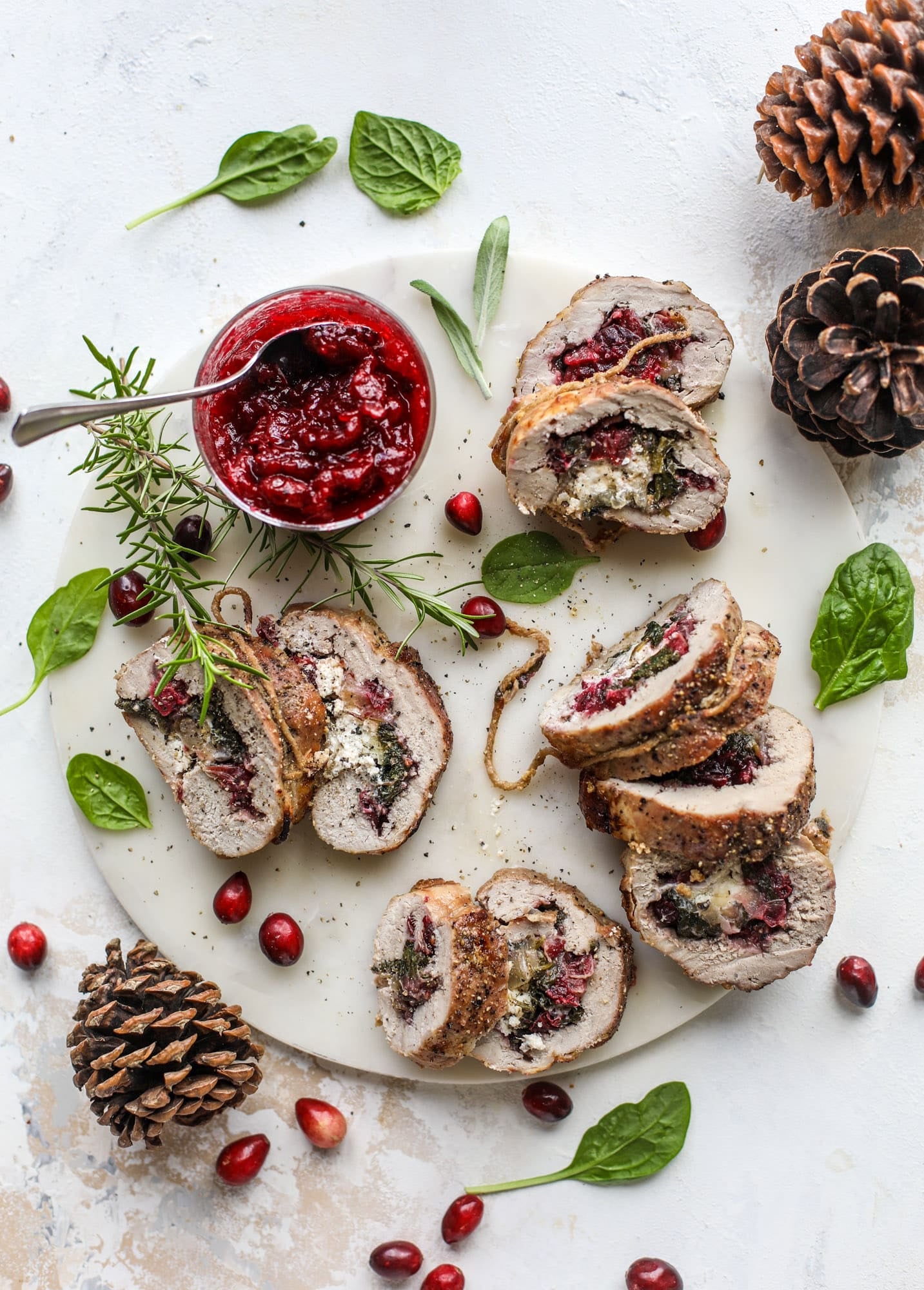 This holiday stuffed pork tenderloin is filled with caramelized onion, fresh cranberry sauce, goat cheese and fresh spinach. It's a show stopped and super delicious, along with being fairly simple to make! I howsweeteats.com #stuffed #porktenderloin