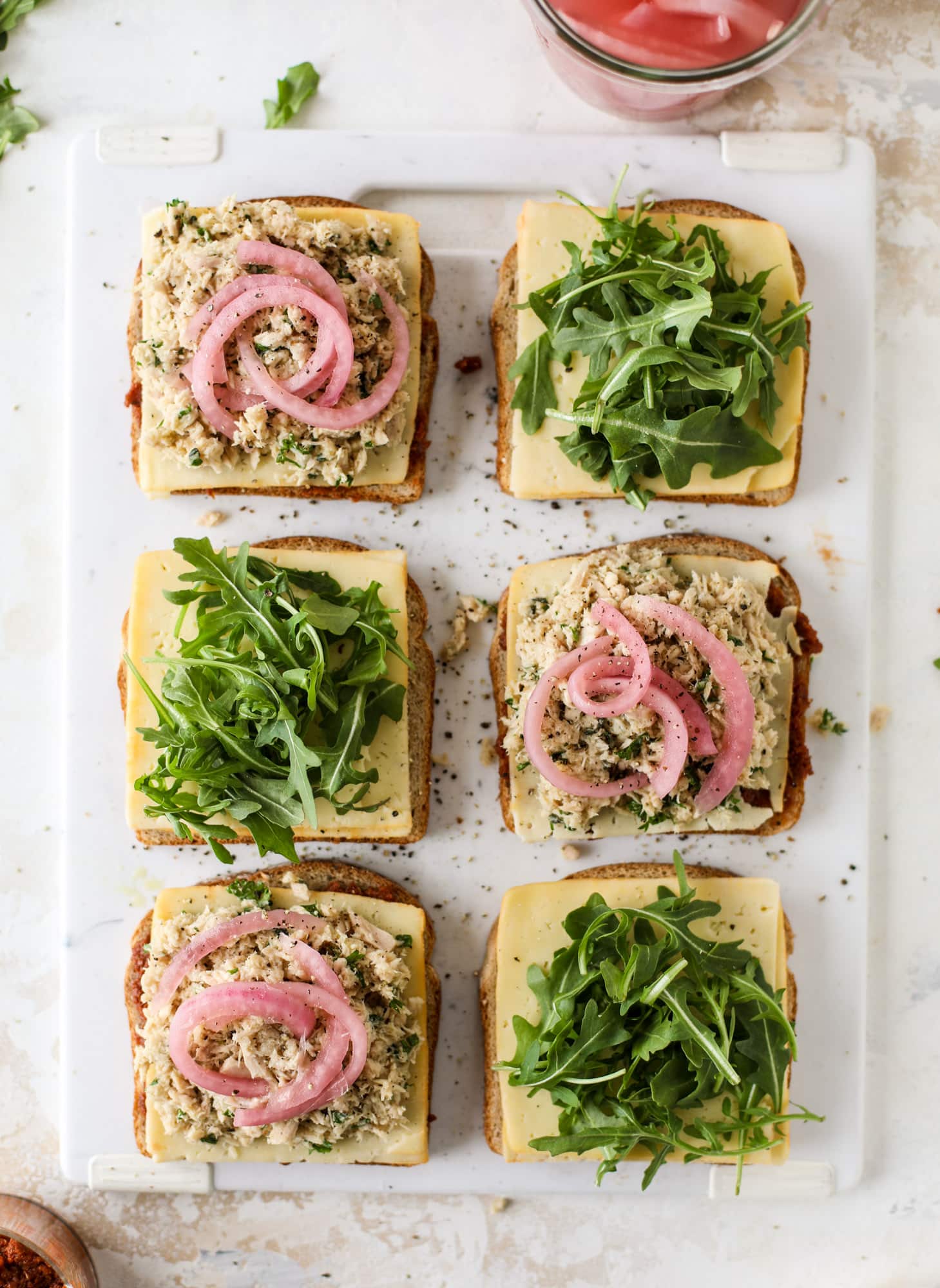 This tuscan tuna melt is a modern way to enjoy a tuna sandwich, with peppery arugula, melty cheese, pickled onions and sun dried tomato spread! I howsweeteats.com #tuna #melt