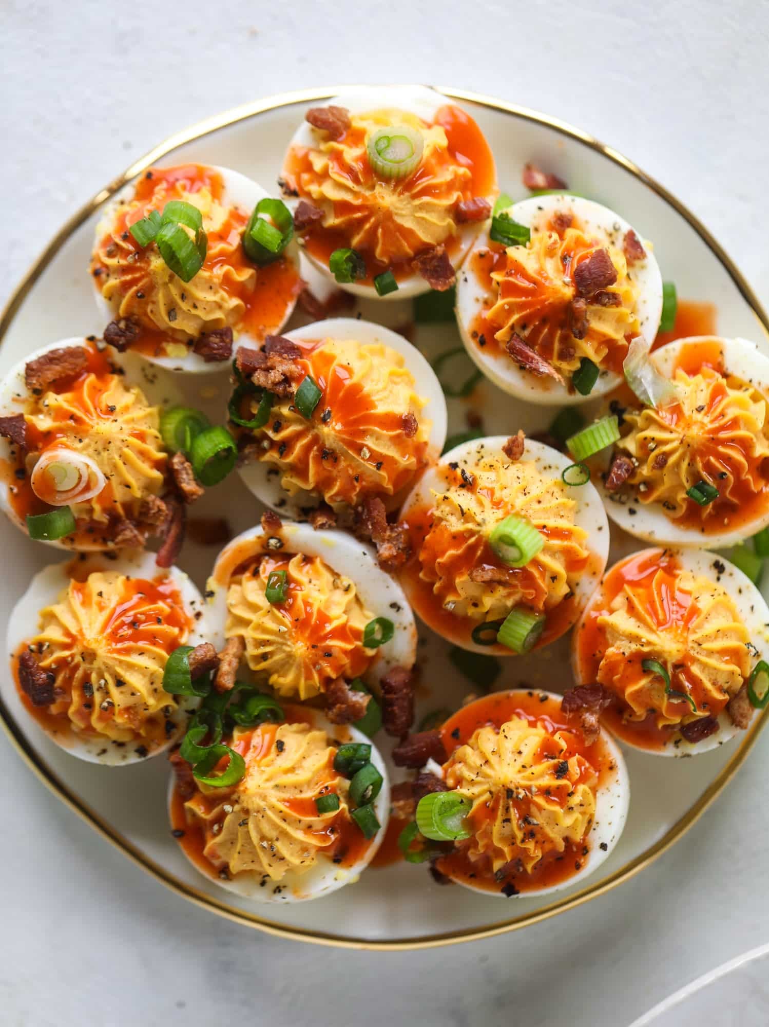Buffalo deviled eggs are kicked-up deviled eggs! Made with goat cheese filling and served with buffalo wing sauce, crispy bacon and sliced scallions. I howsweeteats.com #deviledeggs #buffalo