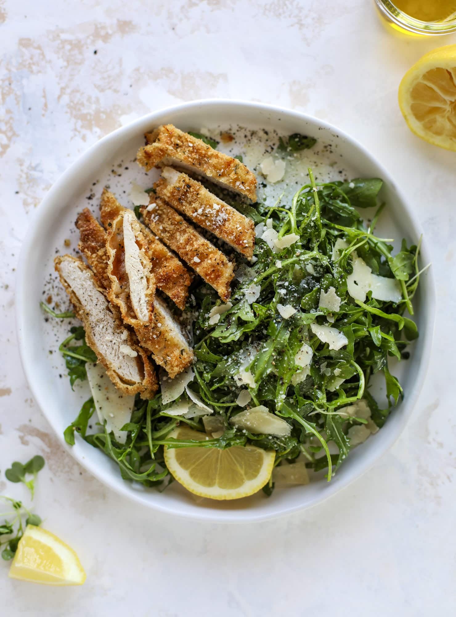 Crispy baked parmesan chicken is so super easy and delicious! It's an amazing weeknight meal served with a lemon arugula salad. Delish!