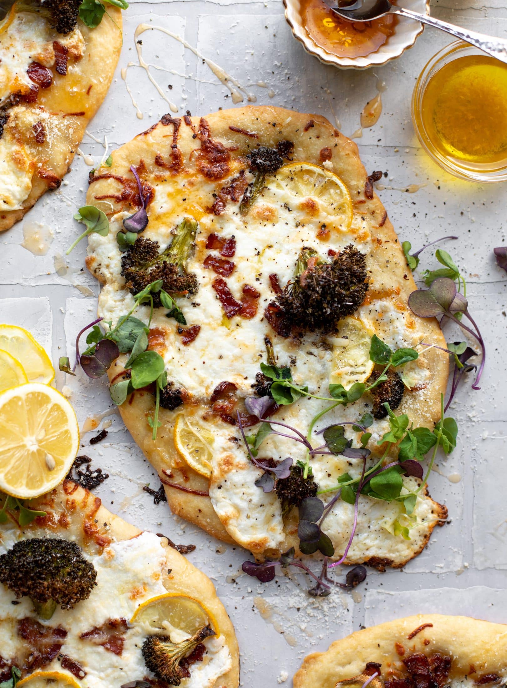 This cheesy lemon flatbread pizza is covered with burrata cheese, parmesan, roasted vegetables and hot honey. It's a flavor dream!