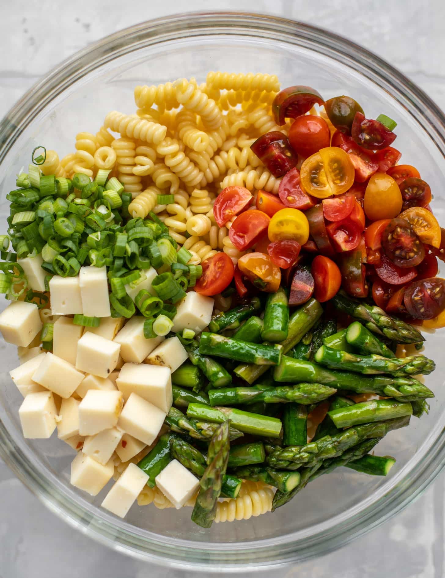 pasta, scallions, tomatoes, asparagus, cheddar in a bowl